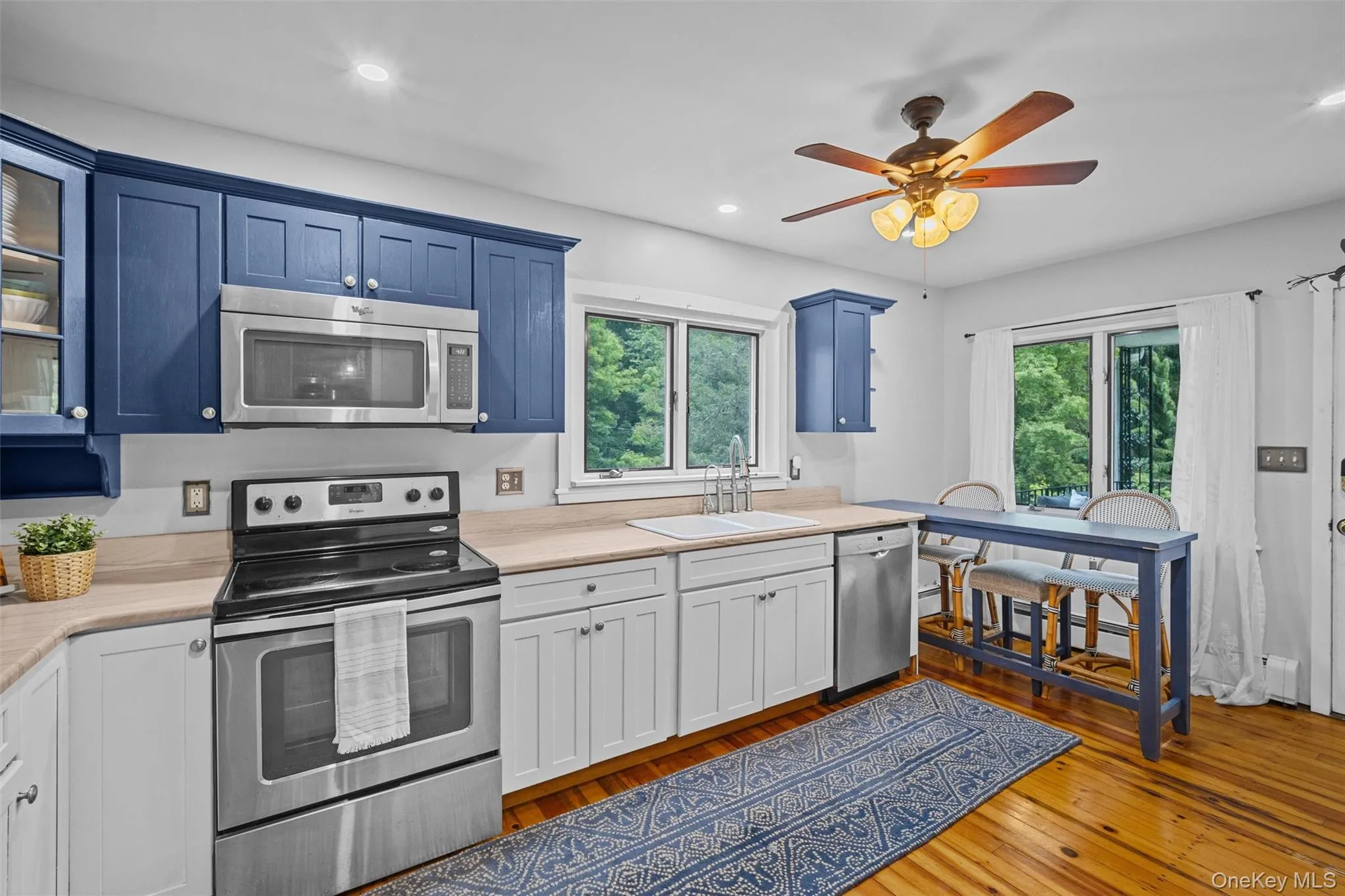 Kitchen with stainless steel appliances, light countertops, plenty of natural light, blue cabinets, and recessed lighting Kitchen with stainless steel appliances, light countertops, plenty of natural light, blue cabinets, and recessed lighting