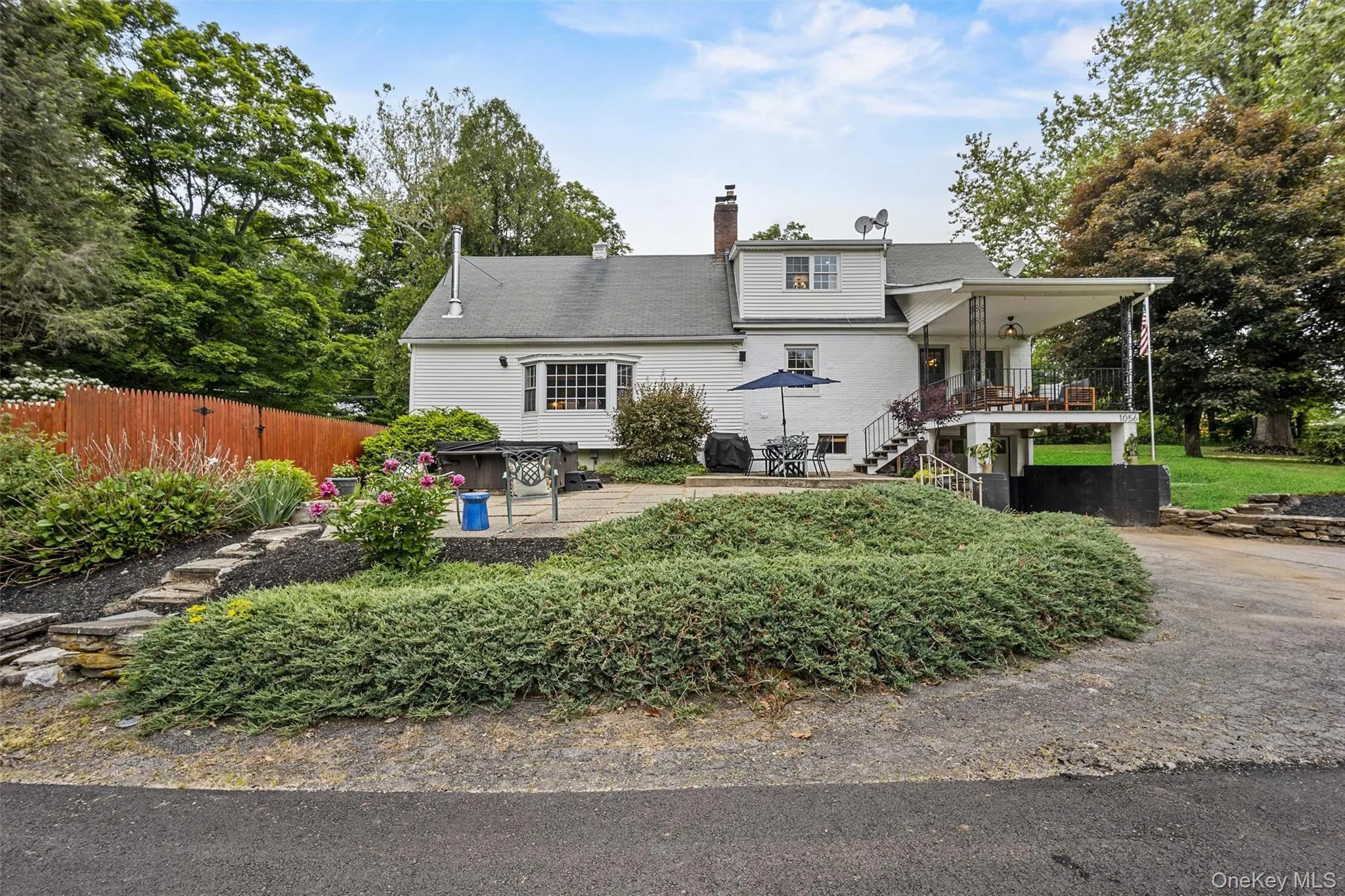 Back of house featuring a chimney, a patio area, and stairway Back of house featuring a chimney, a patio area, and stairway