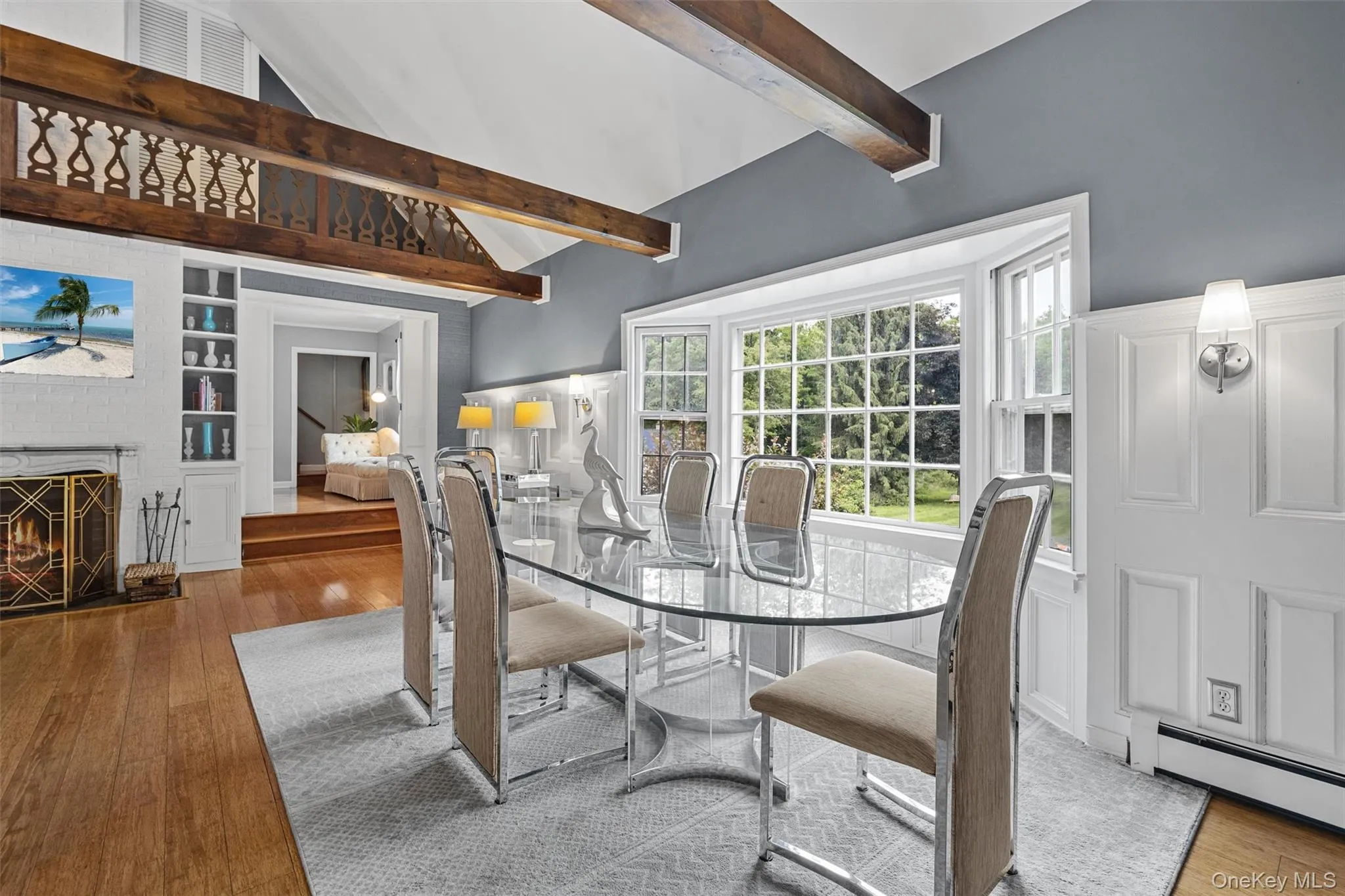 Dining area featuring hardwood / wood-style floors, baseboard heating, beam ceiling, built in shelves, and high vaulted ceiling Dining area featuring hardwood / wood-style floors, baseboard heating, beam ceiling, built in shelves, and high vaulted ceiling