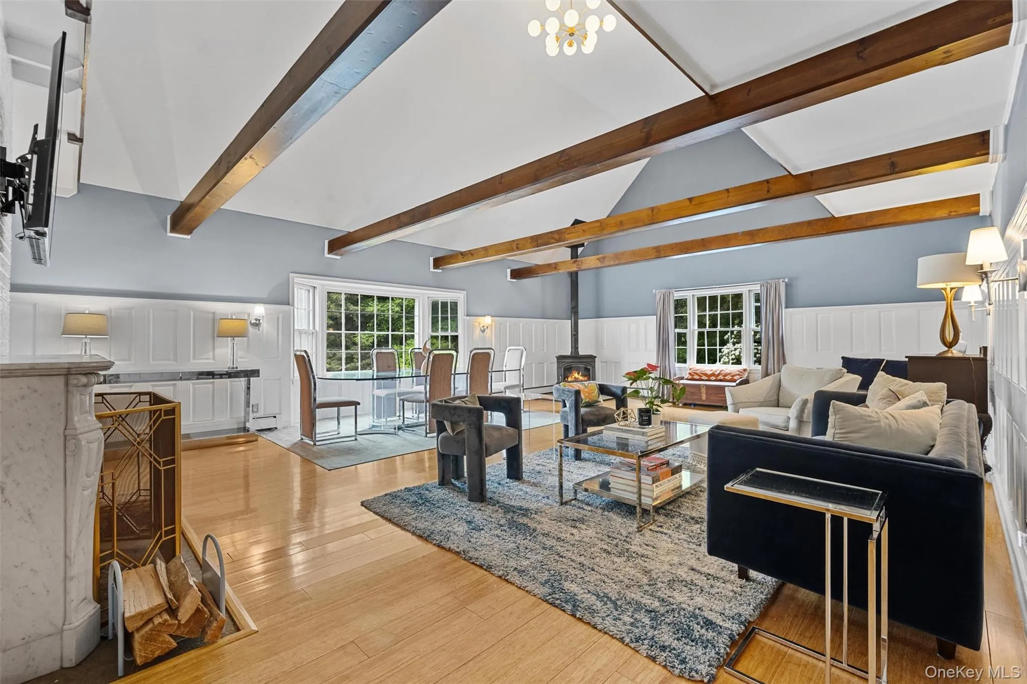 Living area with a wood stove, light wood-style floors, and wainscoting Living area with a wood stove, light wood-style floors, and wainscoting