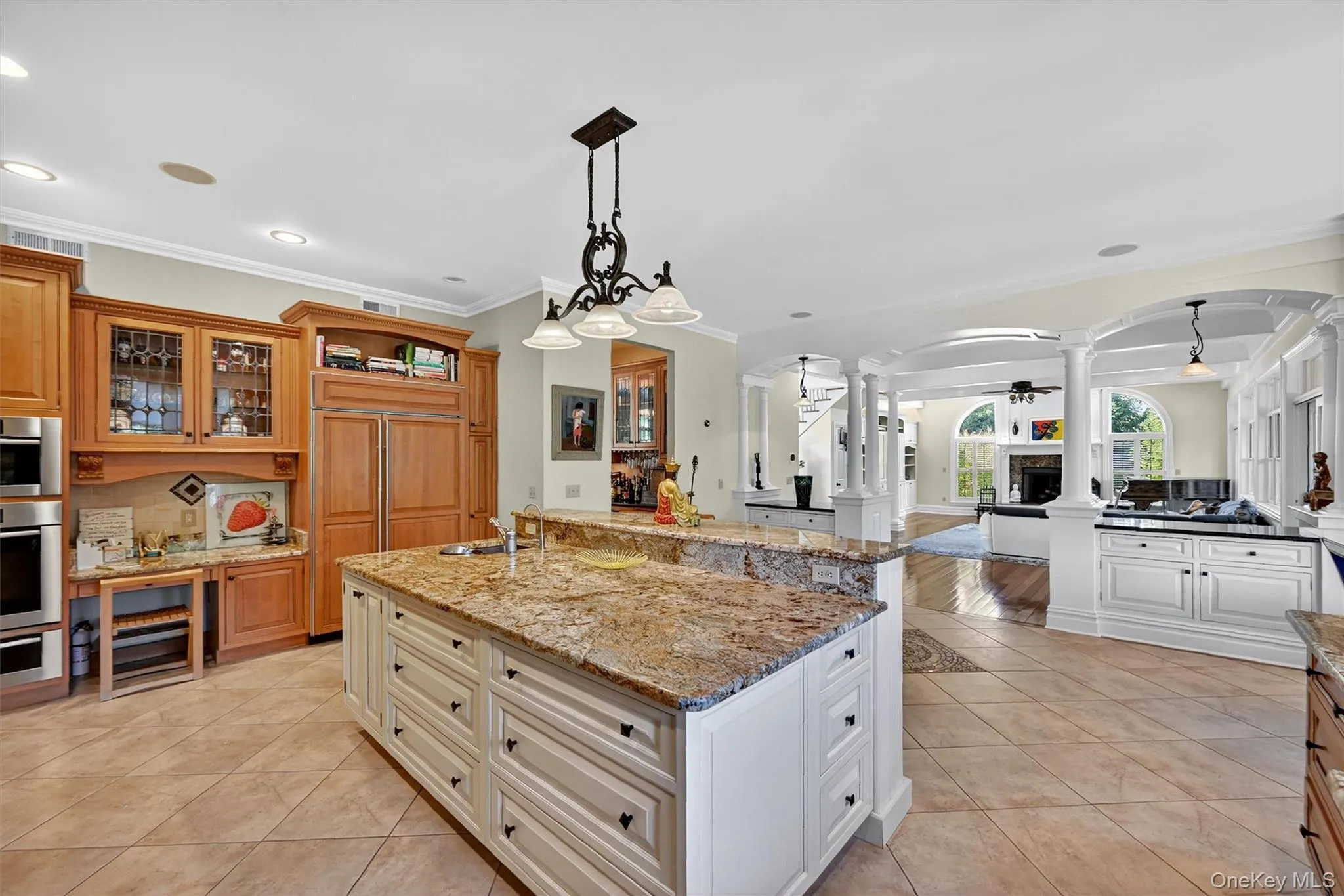 Kitchen with decorative columns, arched walkways, ornamental molding, glass insert cabinets, and light tile patterned floors Kitchen with decorative columns, arched walkways, ornamental molding, glass insert cabinets, and light tile patterned floors