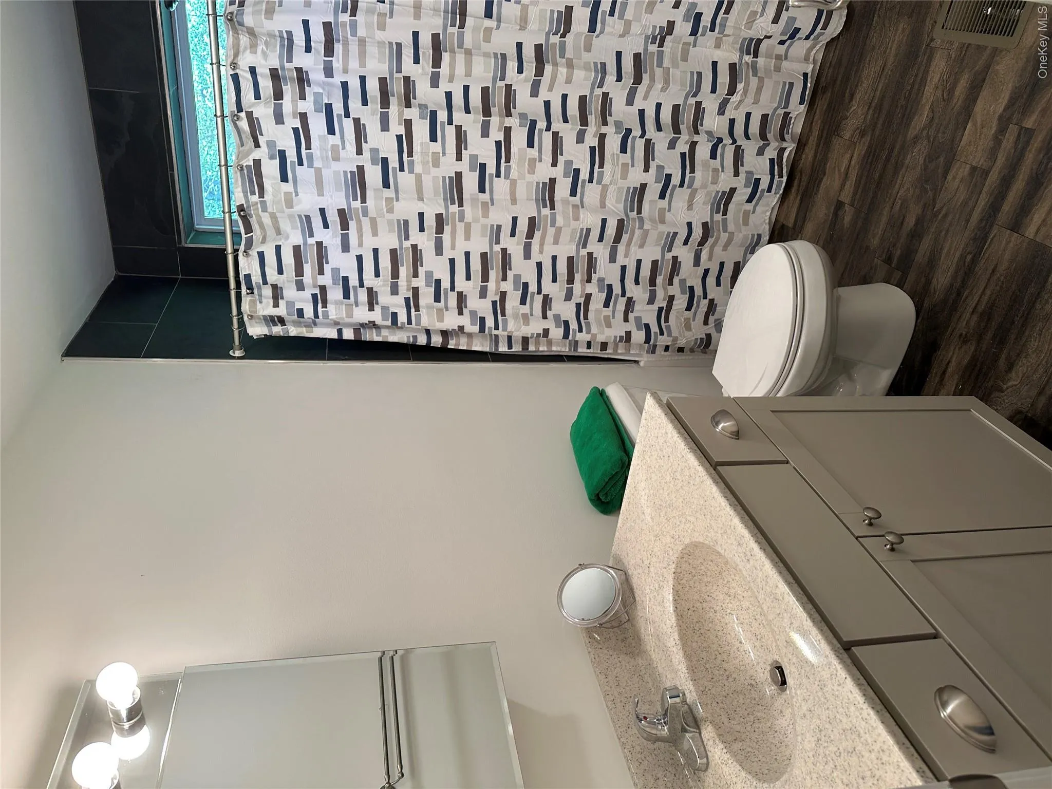 Full bath featuring vanity, a tile shower, and dark wood-type flooring Full bath featuring vanity, a tile shower, and dark wood-type flooring