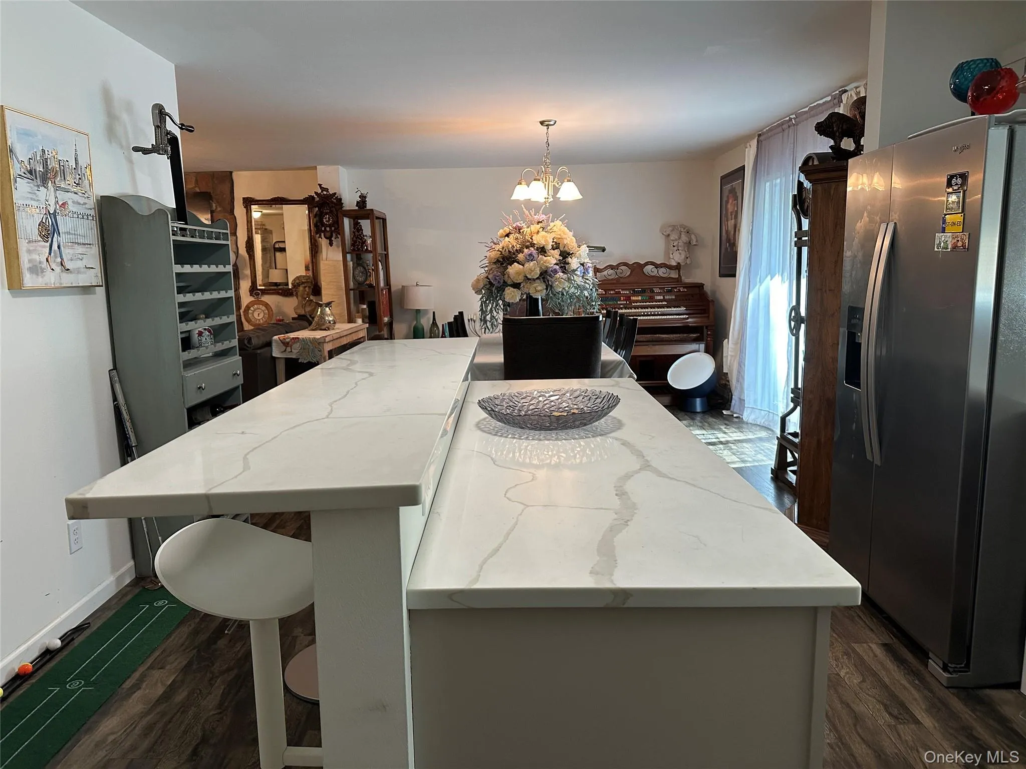 Kitchen with stainless steel fridge, light stone countertops, a chandelier, dark wood finished floors, and pendant lighting Kitchen with stainless steel fridge, light stone countertops, a chandelier, dark wood finished floors, and pendant lighting