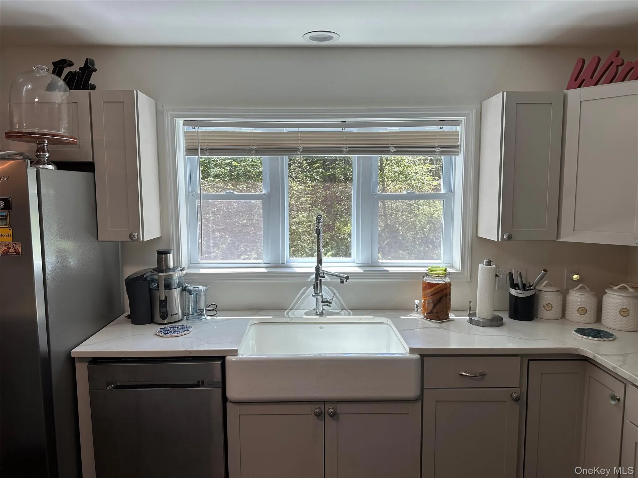 Kitchen with dishwashing machine, plenty of natural light, and light stone counters Kitchen with dishwashing machine, plenty of natural light, and light stone counters