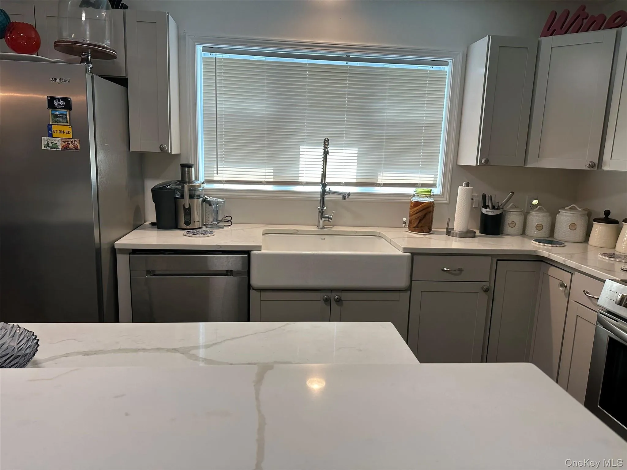 Kitchen featuring appliances with stainless steel finishes, gray cabinets, and light stone countertops Kitchen featuring appliances with stainless steel finishes, gray cabinets, and light stone countertops