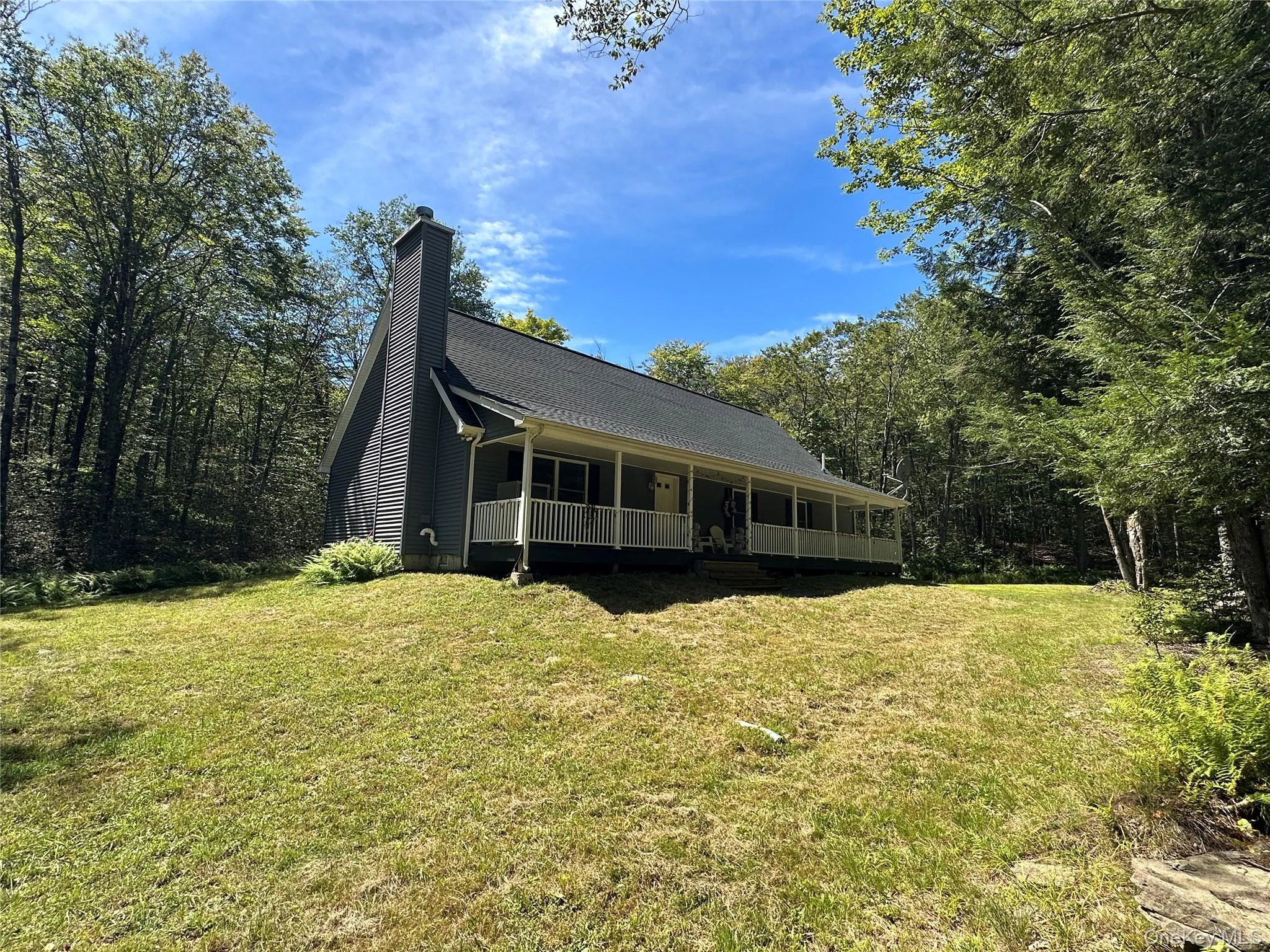 View of front of home with covered porch, a front yard, and a chimney View of front of home with covered porch, a front yard, and a chimney