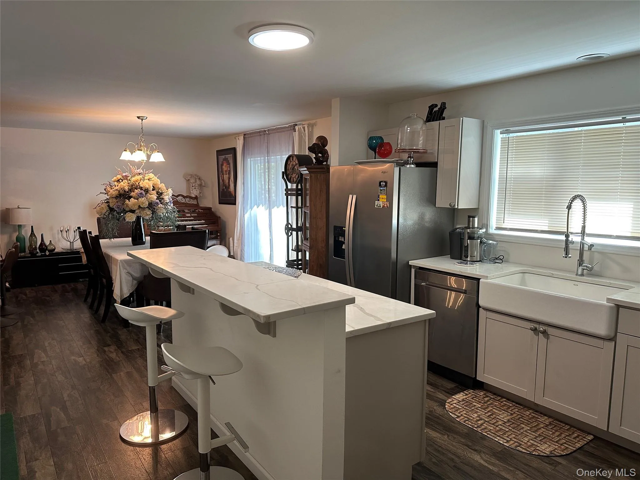 Kitchen featuring a breakfast bar area, dark wood-style floors, a kitchen island, stainless steel appliances, and hanging light fixtures Kitchen featuring a breakfast bar area, dark wood-style floors, a kitchen island, stainless steel appliances, and hanging light fixtures