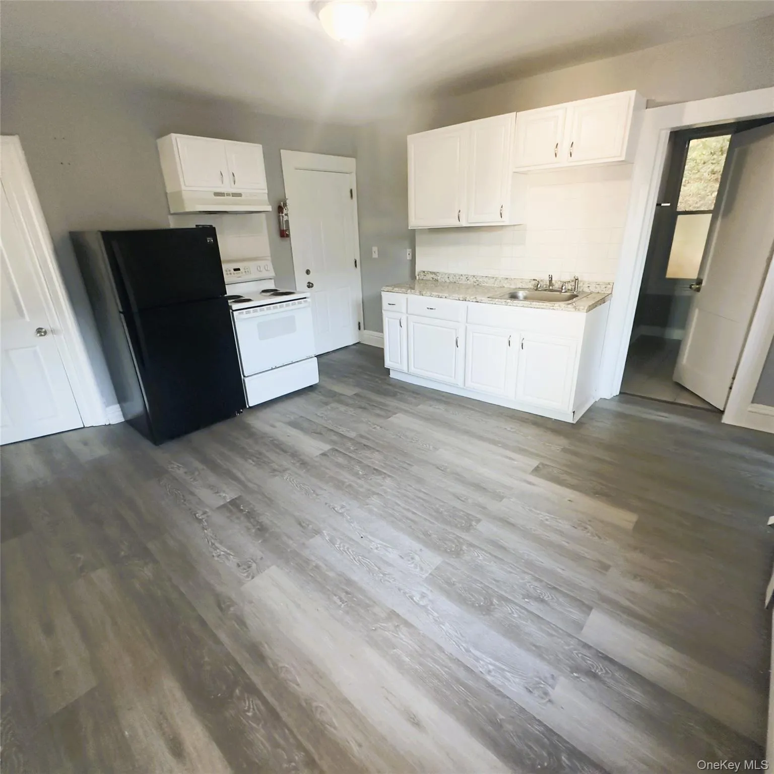 Kitchen with freestanding refrigerator, white electric range, light countertops, and white cabinets vinyl flooring Kitchen with freestanding refrigerator, white electric range, light countertops, and white cabinets vinyl flooring