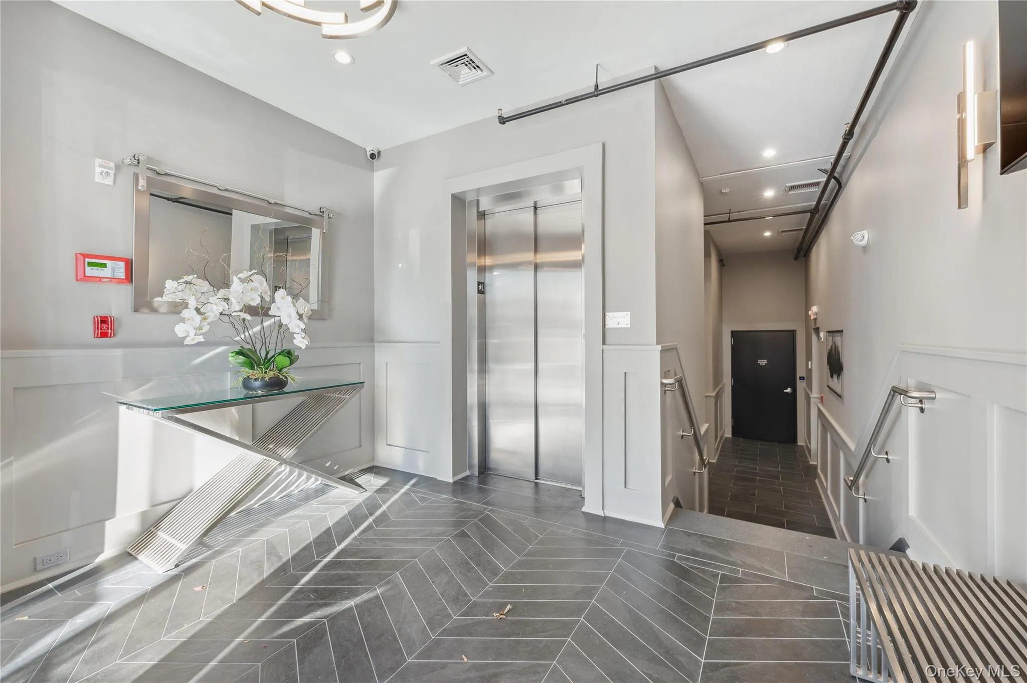 Hall featuring a decorative wall, recessed lighting, a wainscoted wall, elevator, and an upstairs landing Hall featuring a decorative wall, recessed lighting, a wainscoted wall, elevator, and an upstairs landing