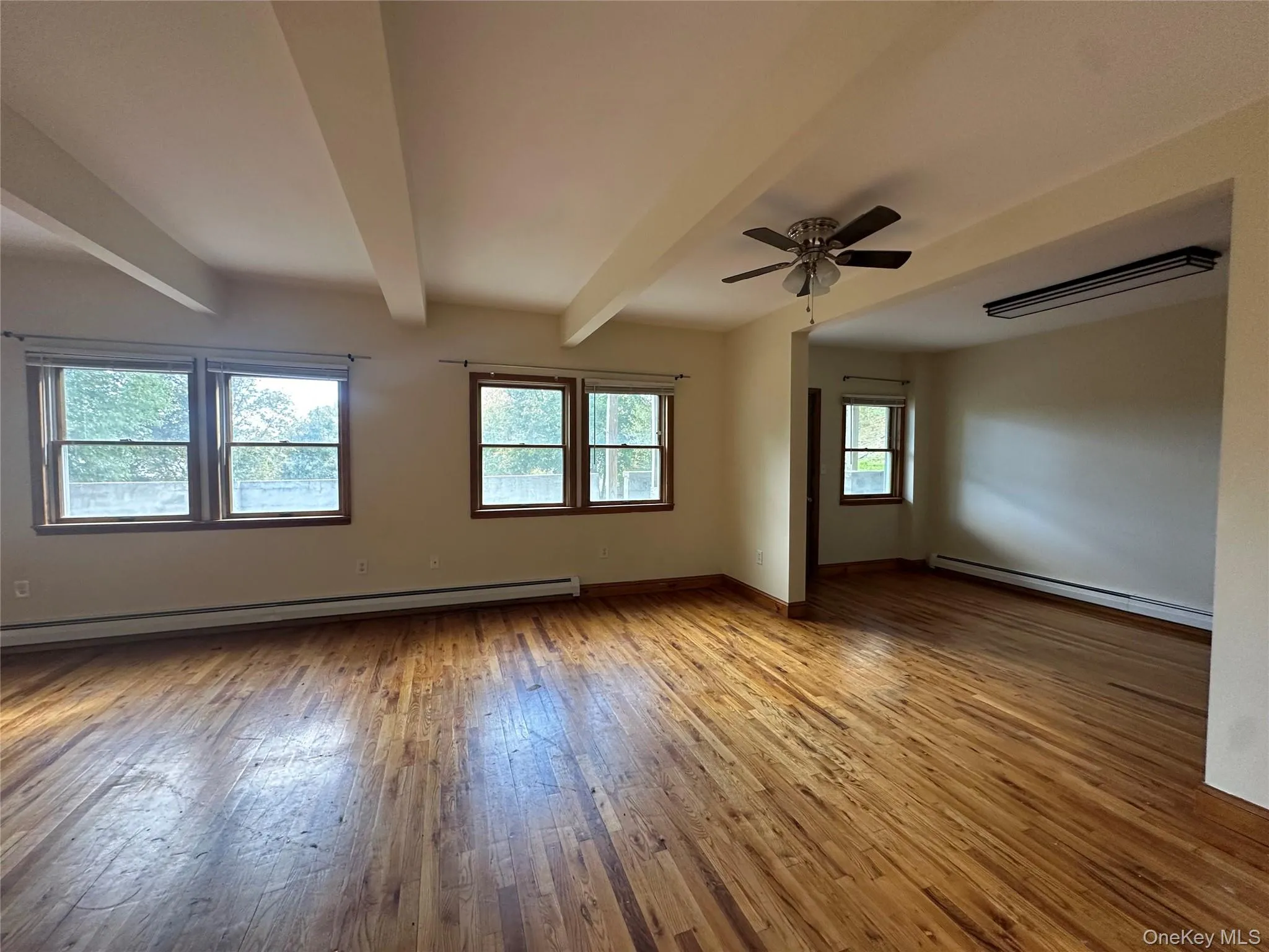 Spare room featuring light wood-type flooring, beamed ceiling, baseboard heating, and ceiling fan Spare room featuring light wood-type flooring, beamed ceiling, baseboard heating, and ceiling fan
