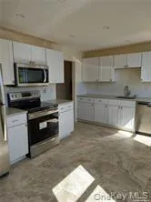 Kitchen featuring white cabinets, stainless steel appliances, and light countertops Kitchen featuring white cabinets, stainless steel appliances, and light countertops