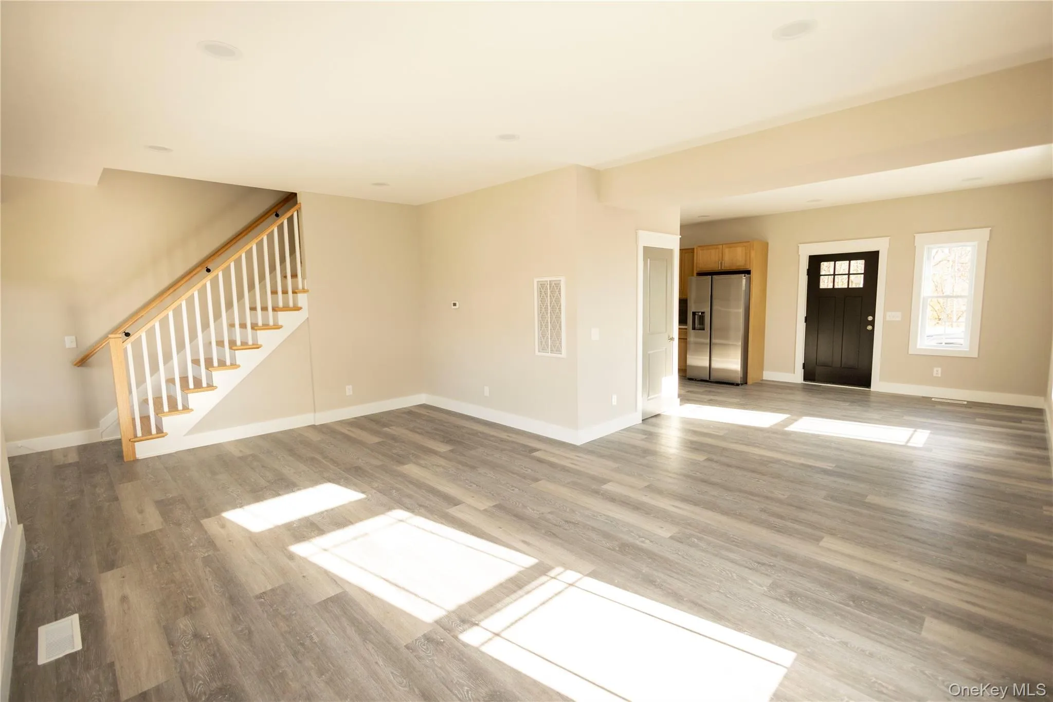 Unfurnished living room featuring light wood-style floors and stairway Unfurnished living room featuring light wood-style floors and stairway
