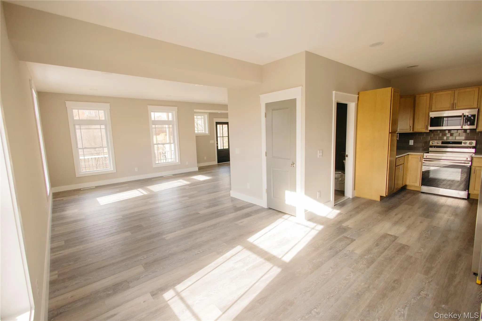 Kitchen featuring stainless steel appliances, light countertops, tasteful backsplash, open floor plan, and light wood-style flooring Kitchen featuring stainless steel appliances, light countertops, tasteful backsplash, open floor plan, and light wood-style flooring