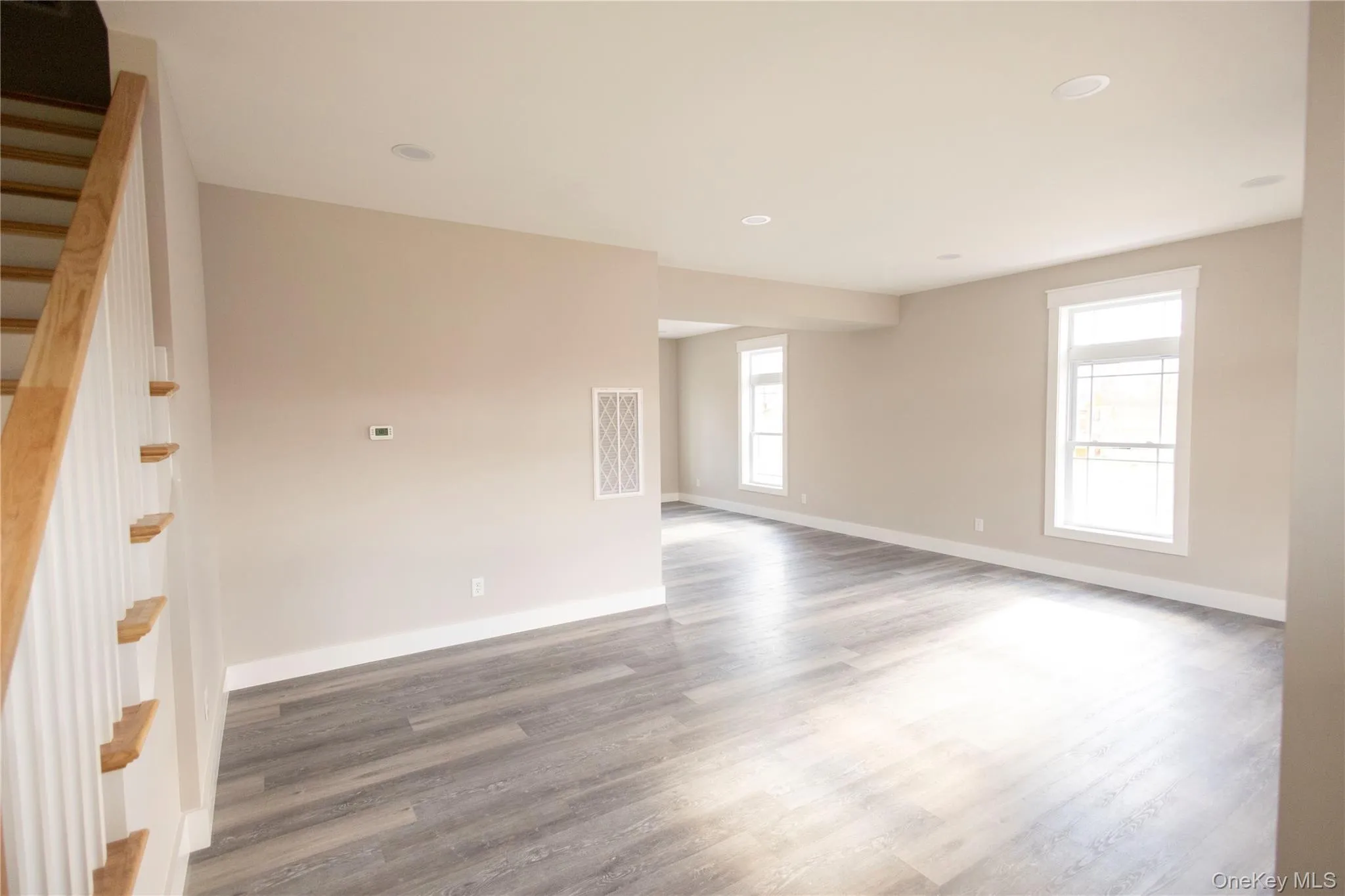 Empty room with plenty of natural light, wood finished floors, stairway, and recessed lighting Empty room with plenty of natural light, wood finished floors, stairway, and recessed lighting