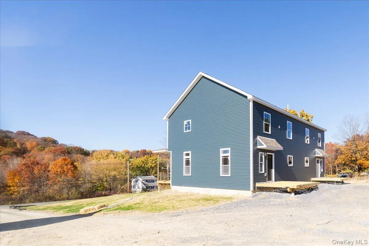Back of house with a lawn, a deck, and a view of trees Back of house with a lawn, a deck, and a view of trees