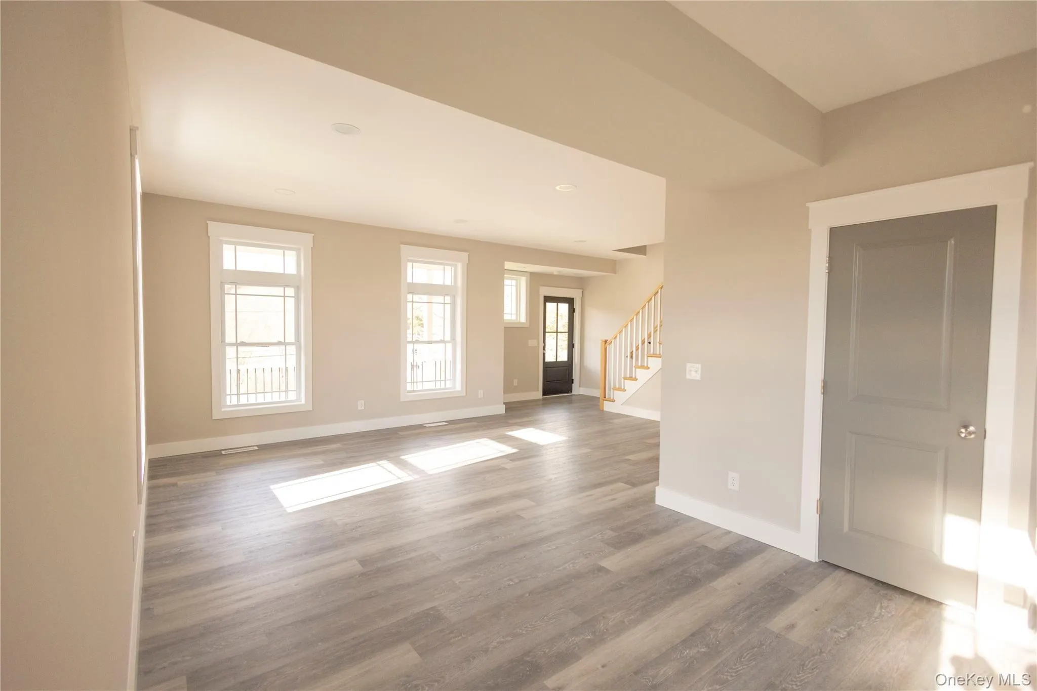 Unfurnished living room with stairway, light wood-style floors, and recessed lighting Unfurnished living room with stairway, light wood-style floors, and recessed lighting