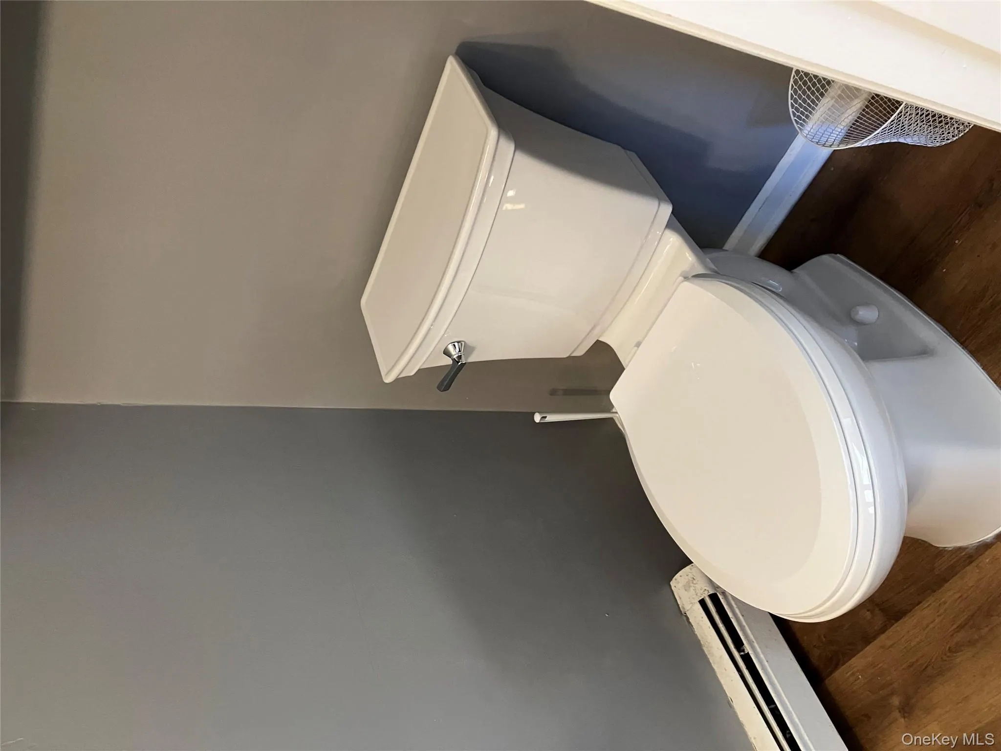 Half bath with a baseboard radiator and dark wood-style flooring Half bath with a baseboard radiator and dark wood-style flooring