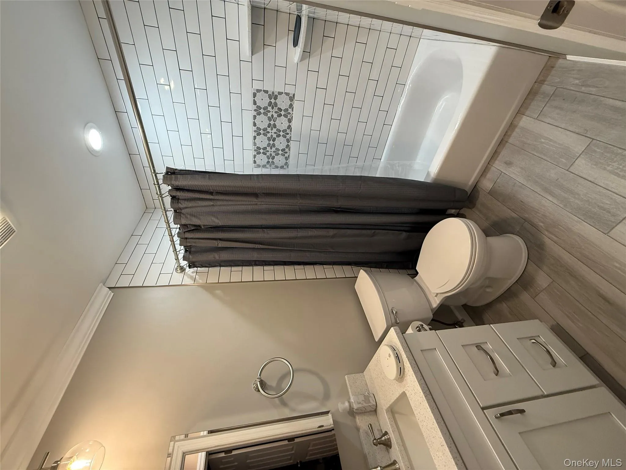 Bathroom featuring wood tiled floors, shower / bathtub combination with curtain, vanity, ornamental molding, and recessed lighting Bathroom featuring wood tiled floors, shower / bathtub combination with curtain, vanity, ornamental molding, and recessed lighting