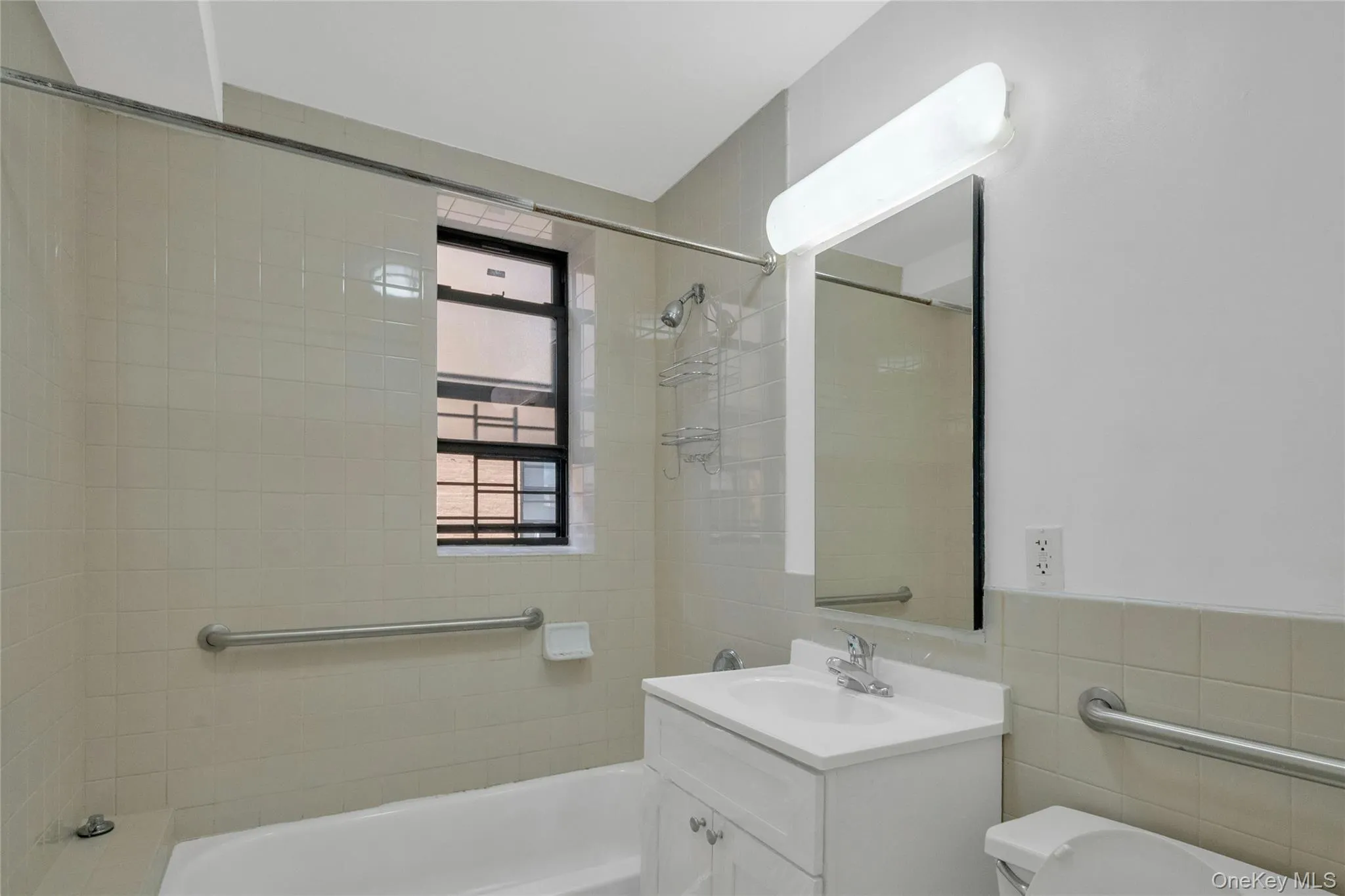 Bathroom featuring shower / washtub combination, vanity, and tile walls Bathroom featuring shower / washtub combination, vanity, and tile walls