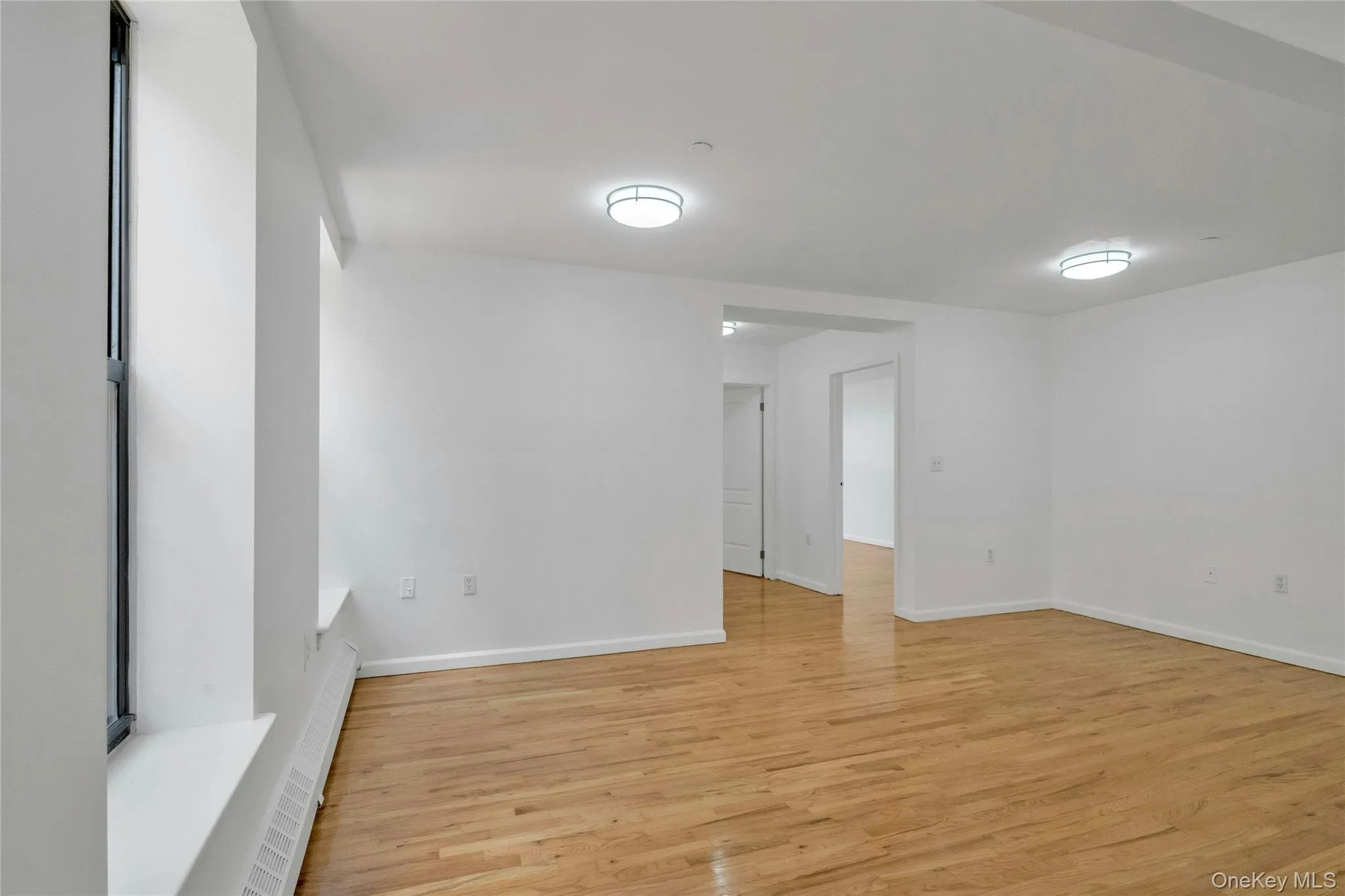 Spare room featuring light wood-style flooring and a baseboard heating unit Spare room featuring light wood-style flooring and a baseboard heating unit