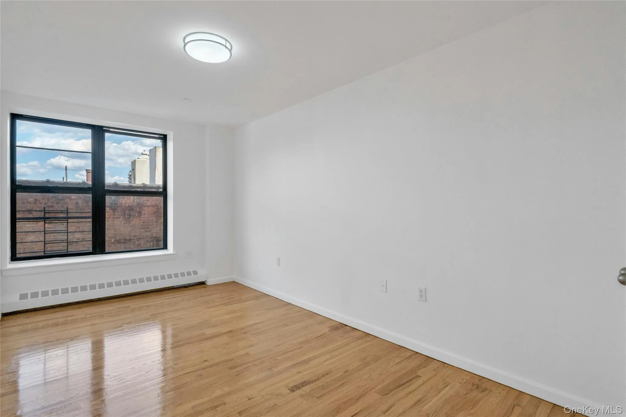 Spare room featuring baseboard heating and light wood-style floors Spare room featuring baseboard heating and light wood-style floors
