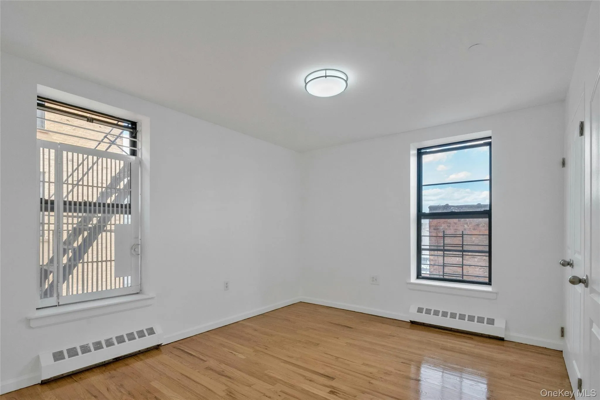 Unfurnished room featuring light wood finished floors and a baseboard heating unit Unfurnished room featuring light wood finished floors and a baseboard heating unit