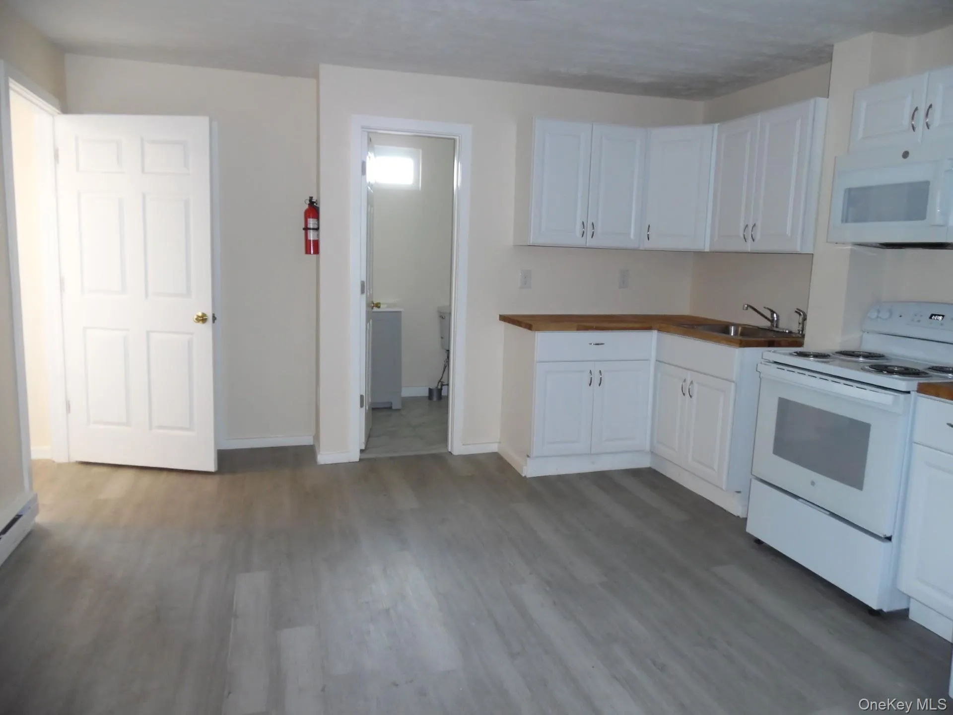 Kitchen with white appliances, dark wood-style flooring, white cabinetry, and butcher block countertops Kitchen with white appliances, dark wood-style flooring, white cabinetry, and butcher block countertops