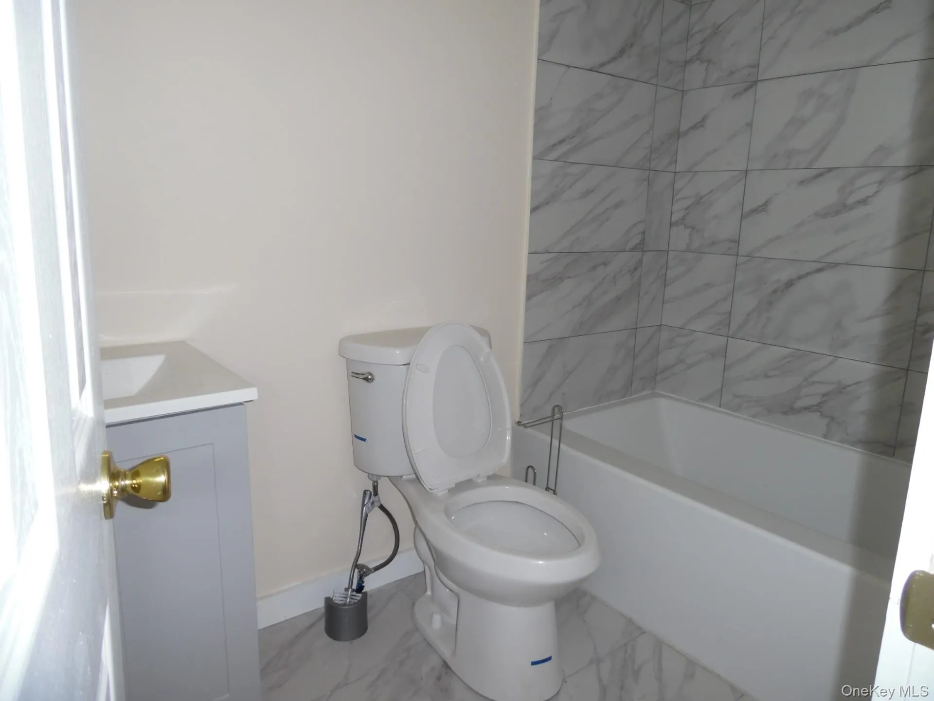 Bathroom featuring vanity, shower / washtub combination, and light marble finish floors Bathroom featuring vanity, shower / washtub combination, and light marble finish floors