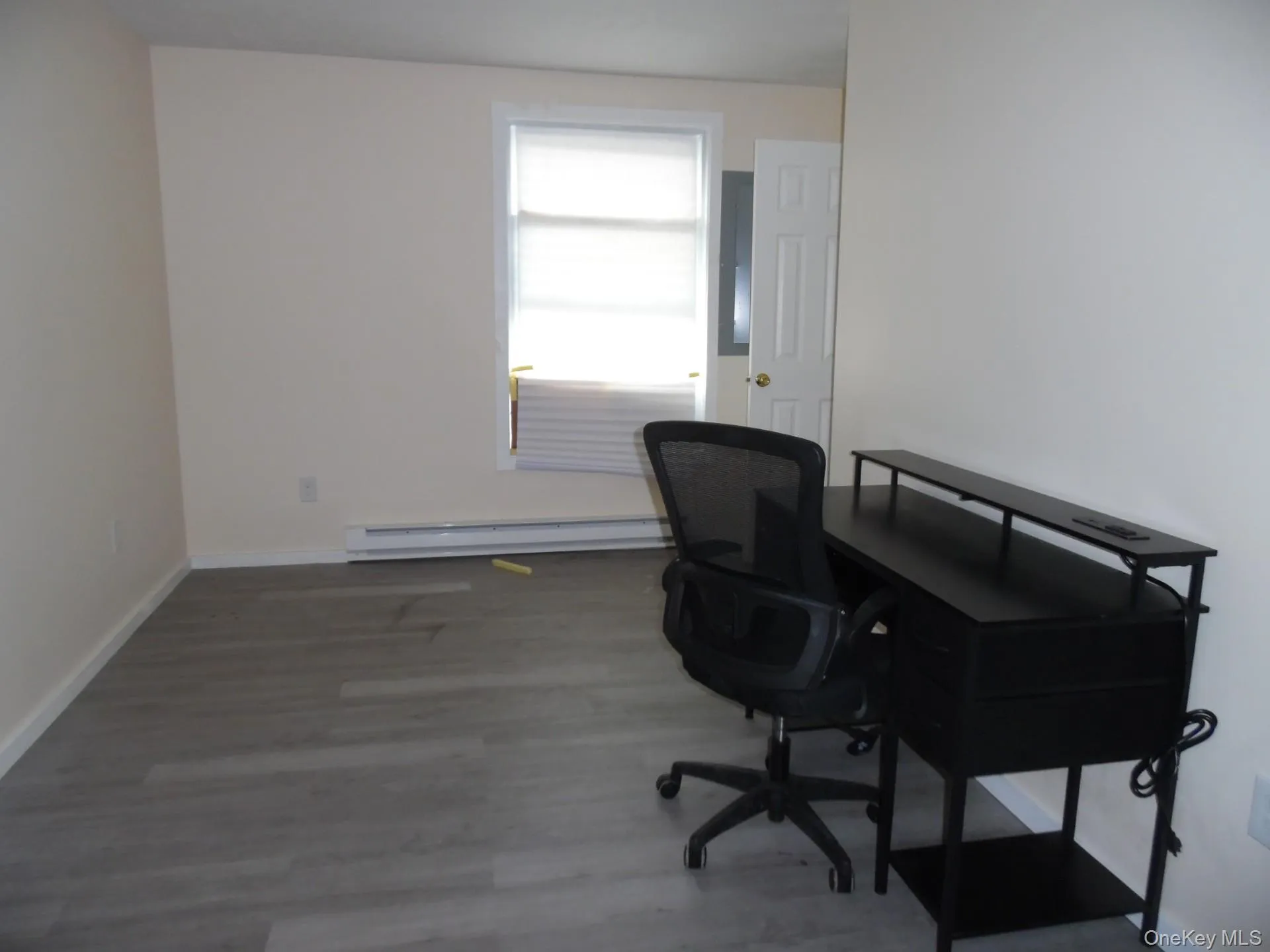 Office space featuring wood finished floors and baseboard heating Office space featuring wood finished floors and baseboard heating