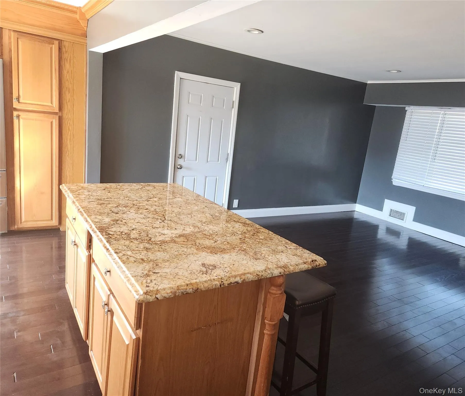 Kitchen with dark wood-style floors, a center island, a breakfast bar area, and light stone counters Kitchen with dark wood-style floors, a center island, a breakfast bar area, and light stone counters