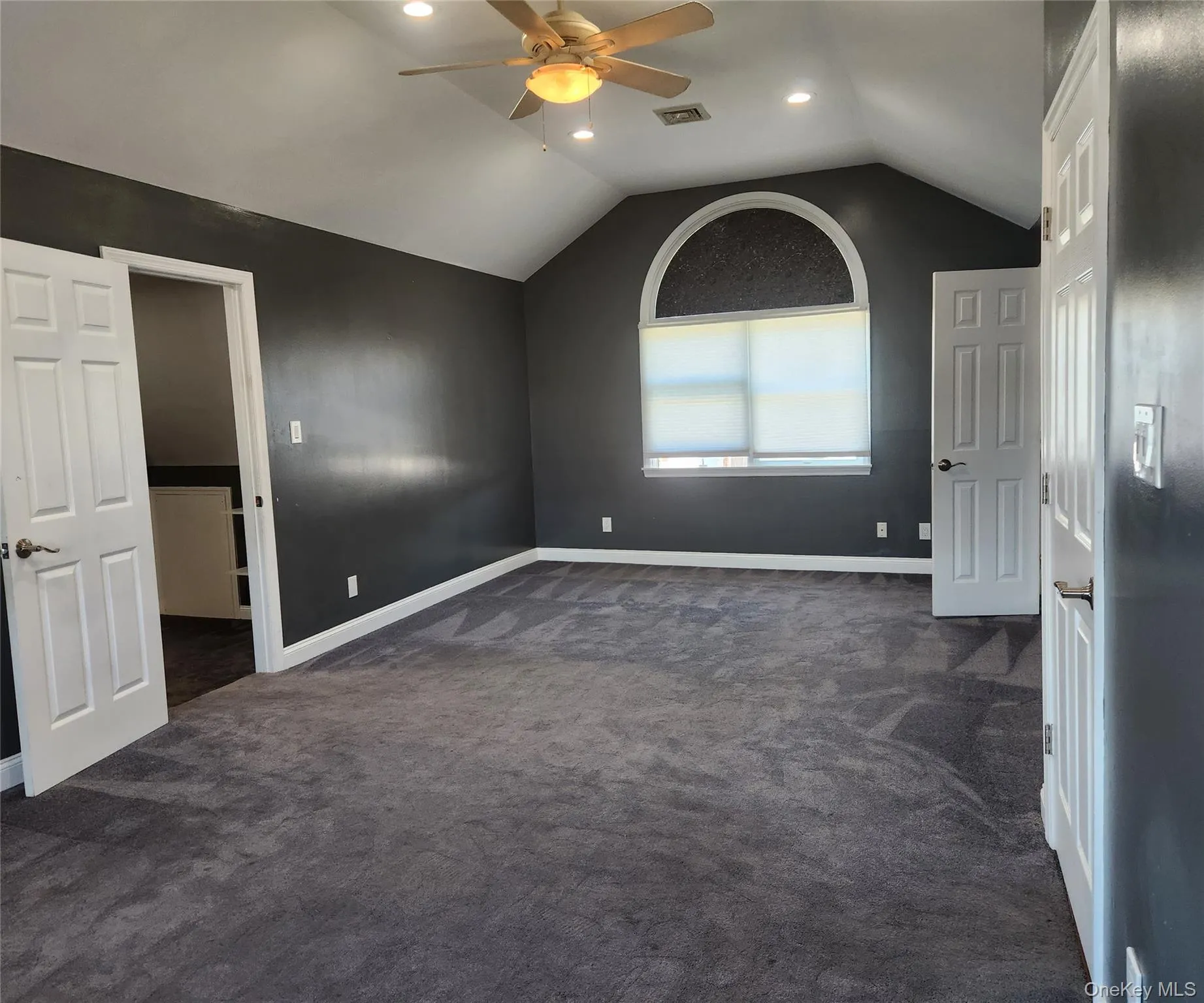 Unfurnished bedroom with dark carpet, lofted ceiling, a ceiling fan, and recessed lighting Unfurnished bedroom with dark carpet, lofted ceiling, a ceiling fan, and recessed lighting