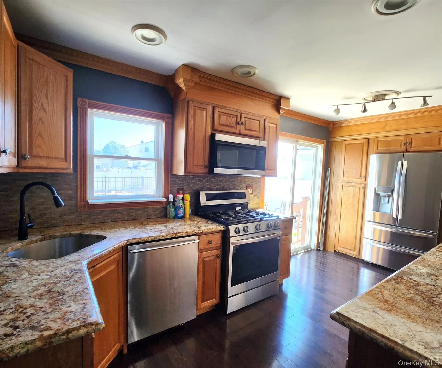 Kitchen with stainless steel appliances, backsplash, healthy amount of natural light, light stone counters, and crown molding Kitchen with stainless steel appliances, backsplash, healthy amount of natural light, light stone counters, and crown molding
