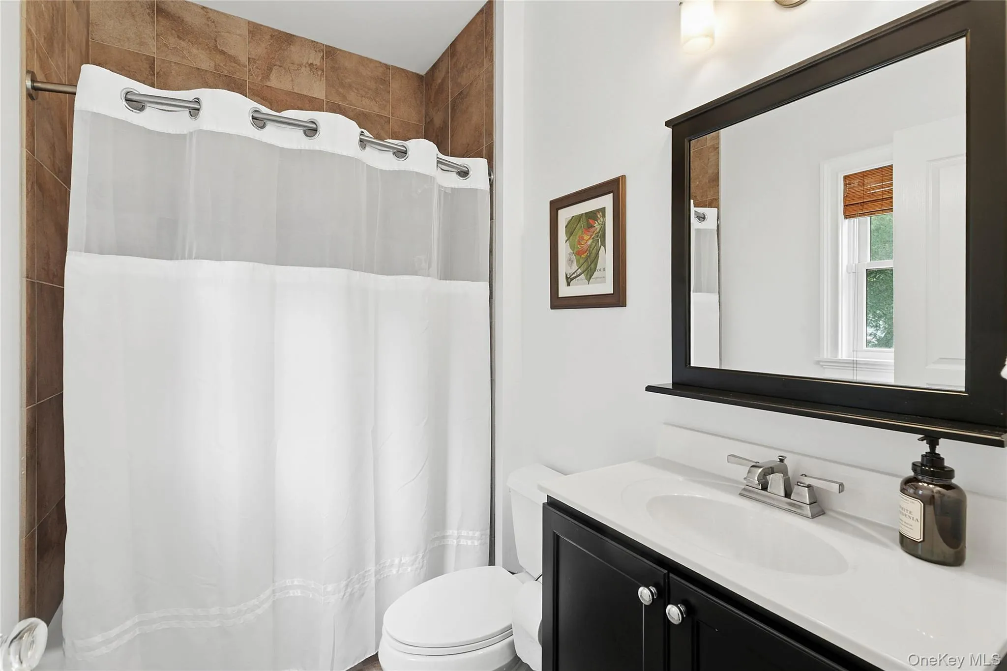 Full bath off bedroom 2 featuring vanity and curtained shower Full bath off bedroom 2 featuring vanity and curtained shower
