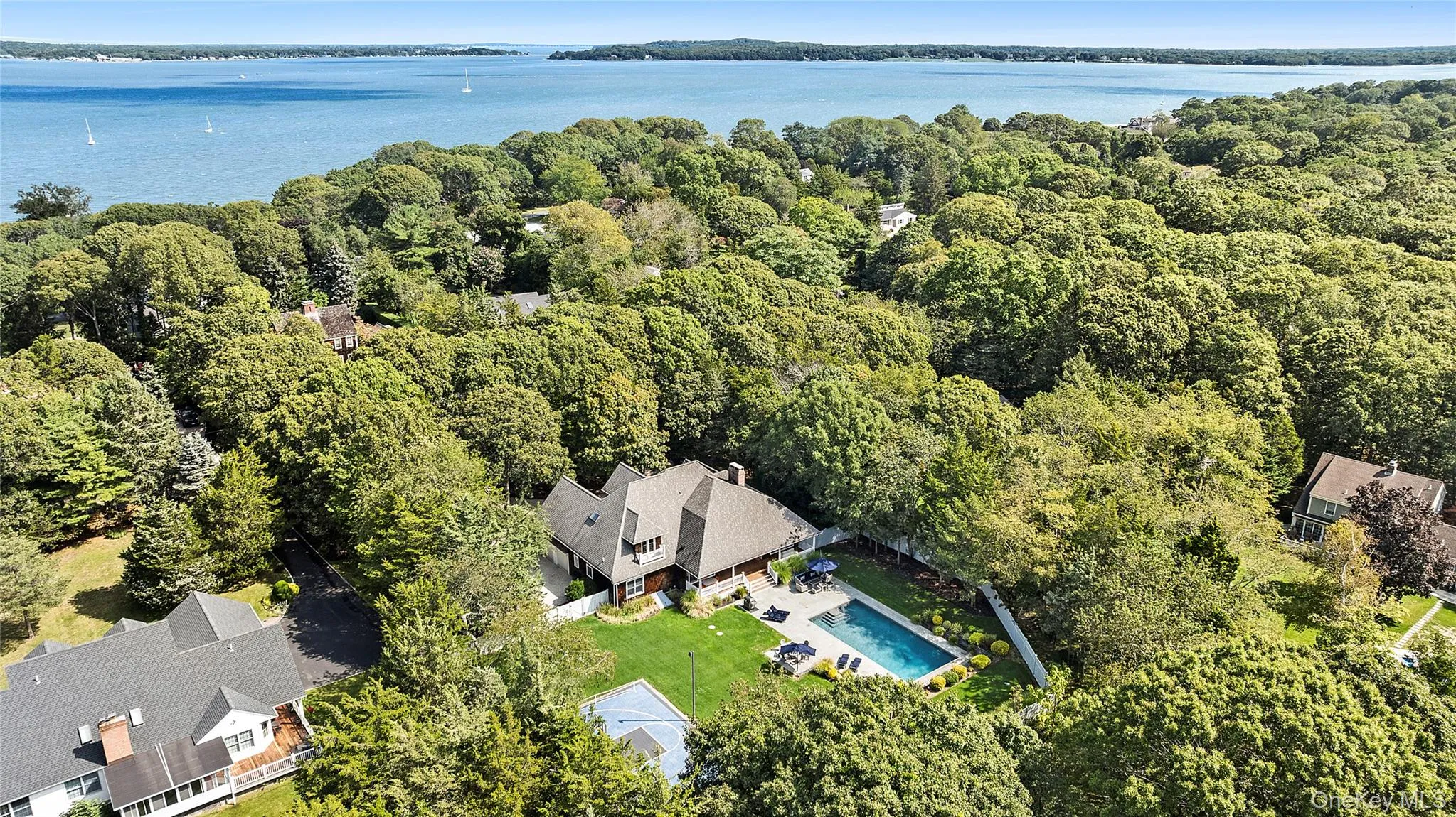 Aerial view of property and surrounding area featuring a pool area and a nearby body of water Aerial view of property and surrounding area featuring a pool area and a nearby body of water