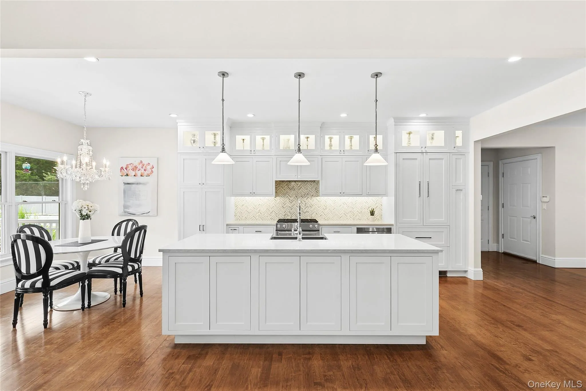 Kitchen with white cabinets, tasteful backsplash, decorative light fixtures, wood finished floors, and recessed lighting Kitchen with white cabinets, tasteful backsplash, decorative light fixtures, wood finished floors, and recessed lighting
