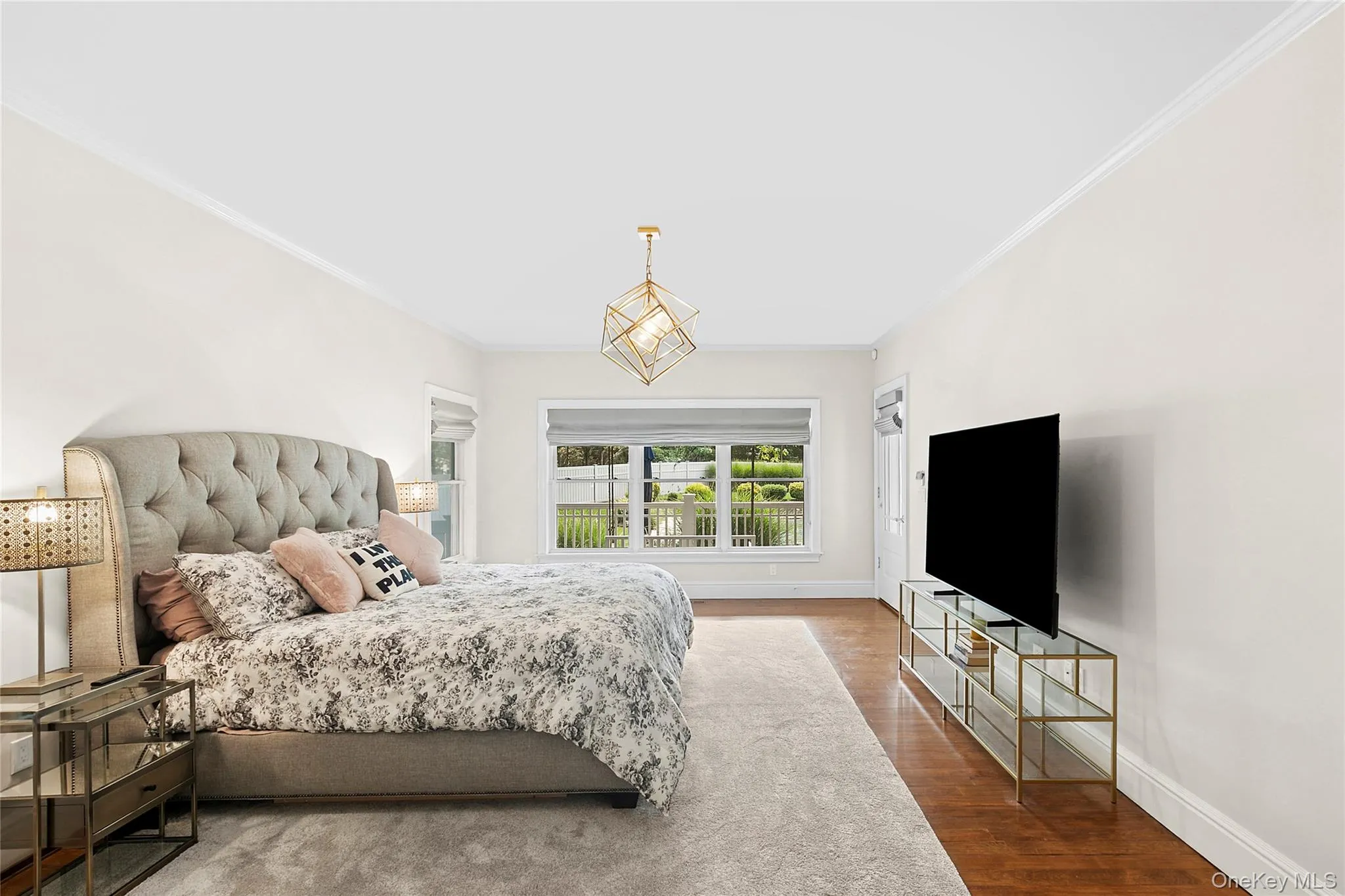Primary Bedroom en suite with ornamental molding, wood finished floors, and a chandelier with access to back deck. Primary Bedroom en suite with ornamental molding, wood finished floors, and a chandelier with access to back deck.