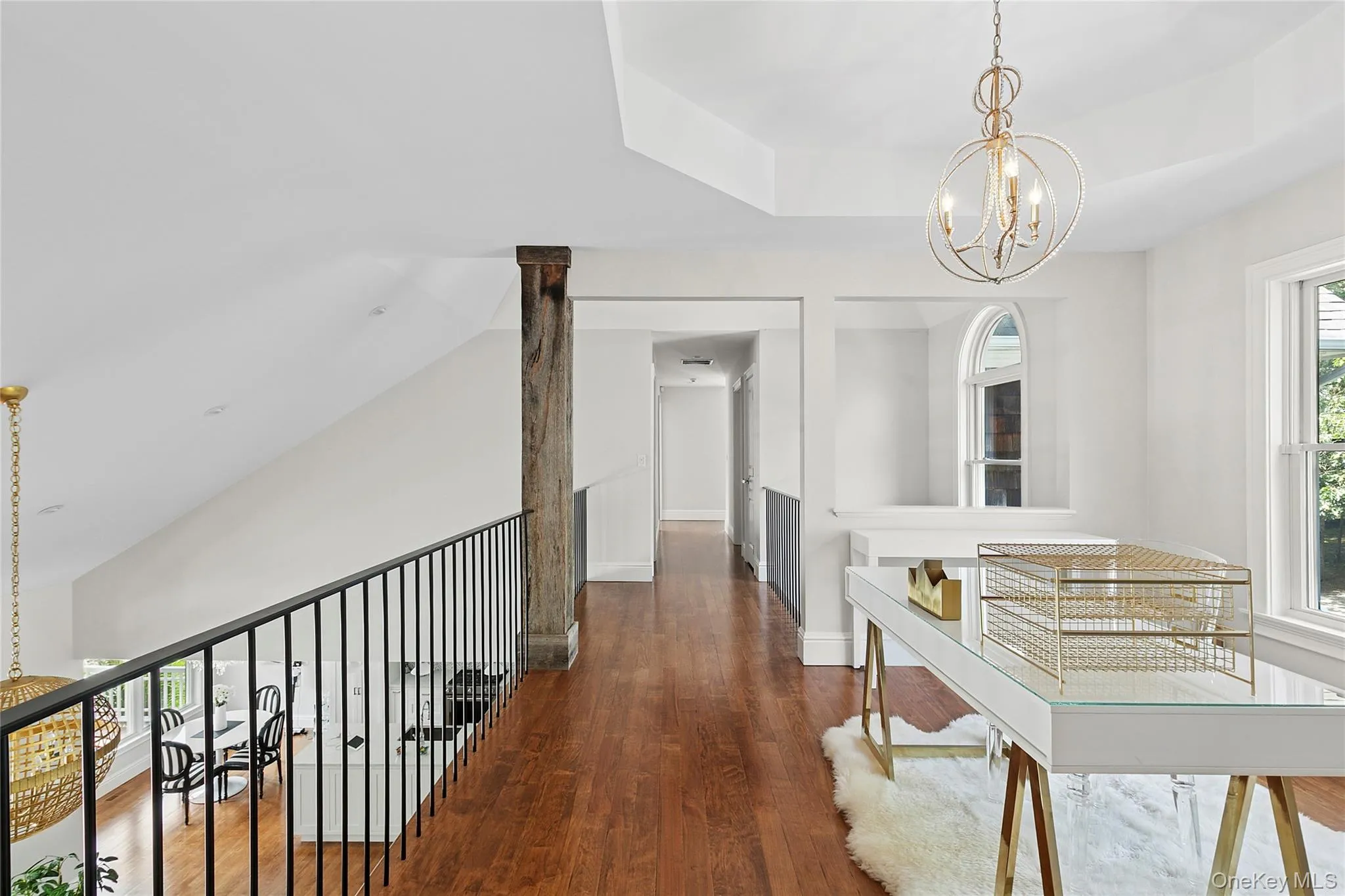Loft area used as an office with a chandelier, wood flooring, and a raised ceiling Loft area used as an office with a chandelier, wood flooring, and a raised ceiling