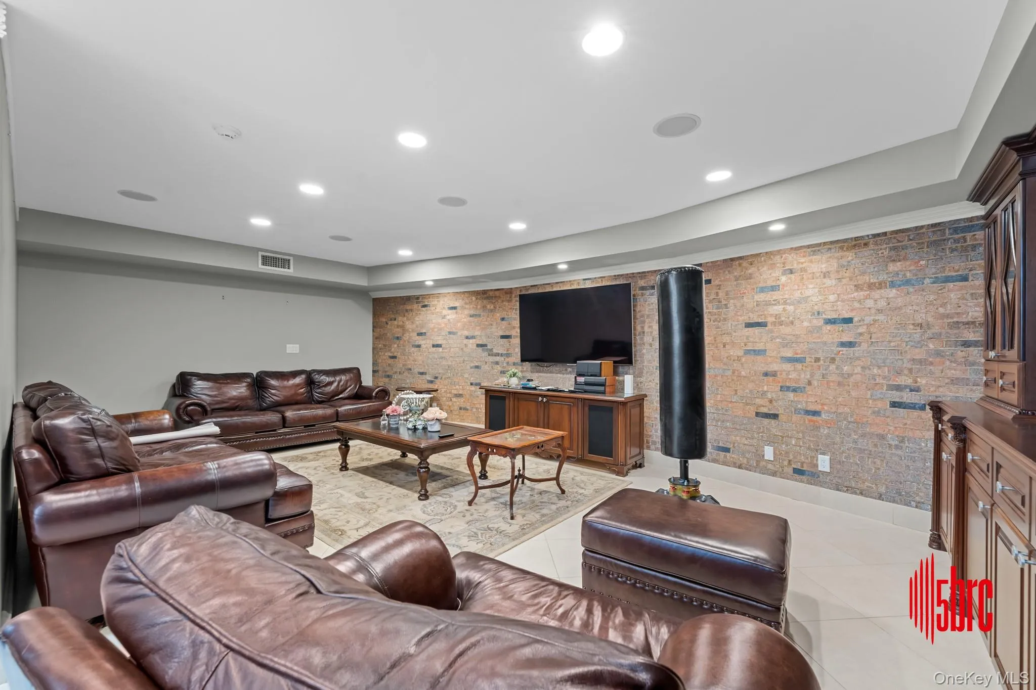 Living area with recessed lighting, brick wall, light tile patterned floors, and a tray ceiling Living area with recessed lighting, brick wall, light tile patterned floors, and a tray ceiling