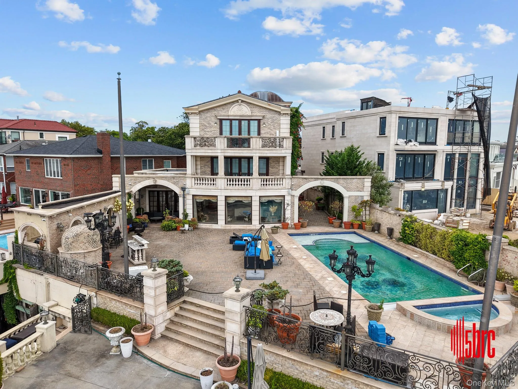 Rear view of house featuring a patio area, a balcony, a pool with connected hot tub, and stone siding Rear view of house featuring a patio area, a balcony, a pool with connected hot tub, and stone siding