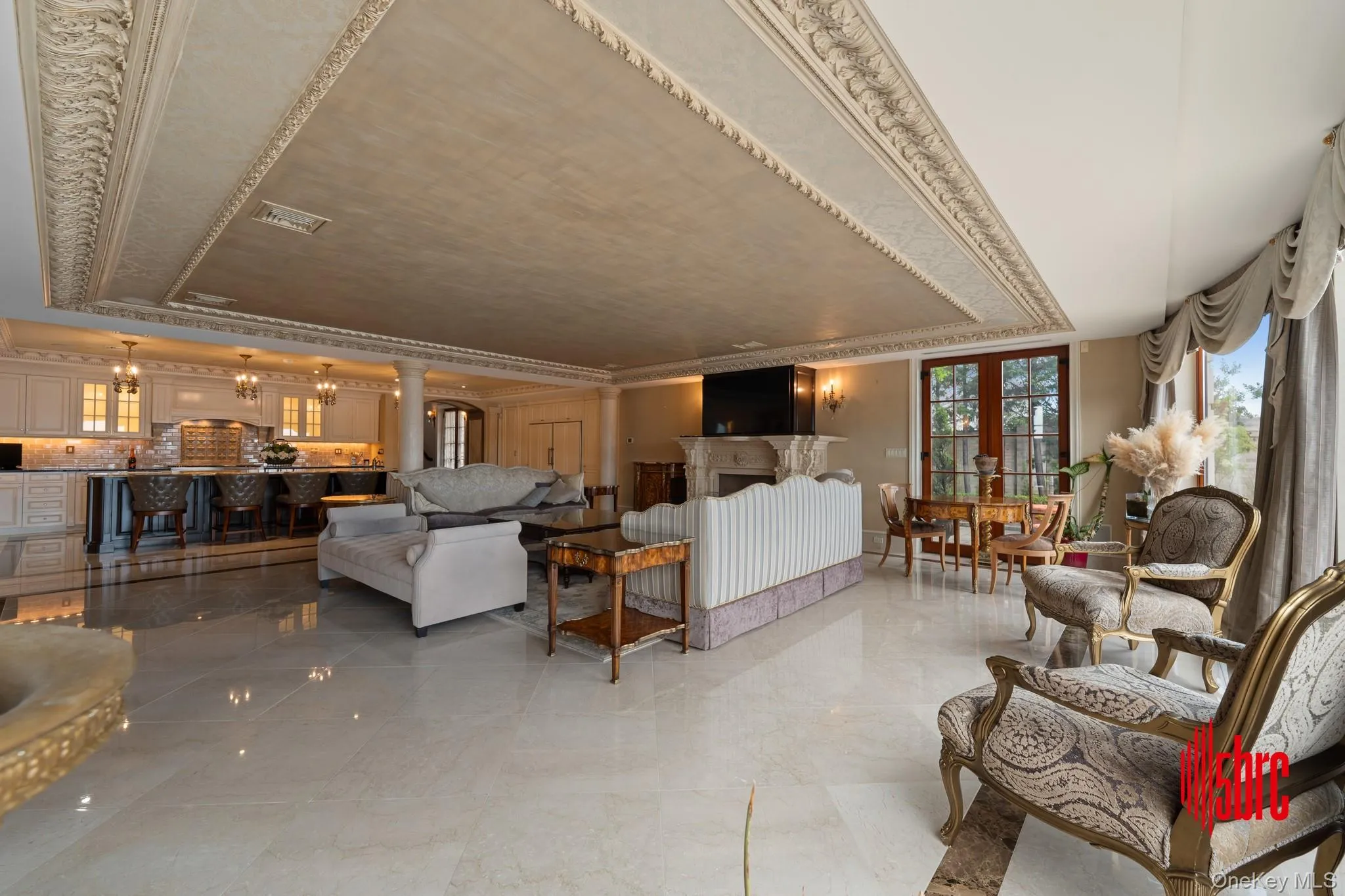 Living room featuring crown molding, a raised ceiling, and decorative columns Living room featuring crown molding, a raised ceiling, and decorative columns