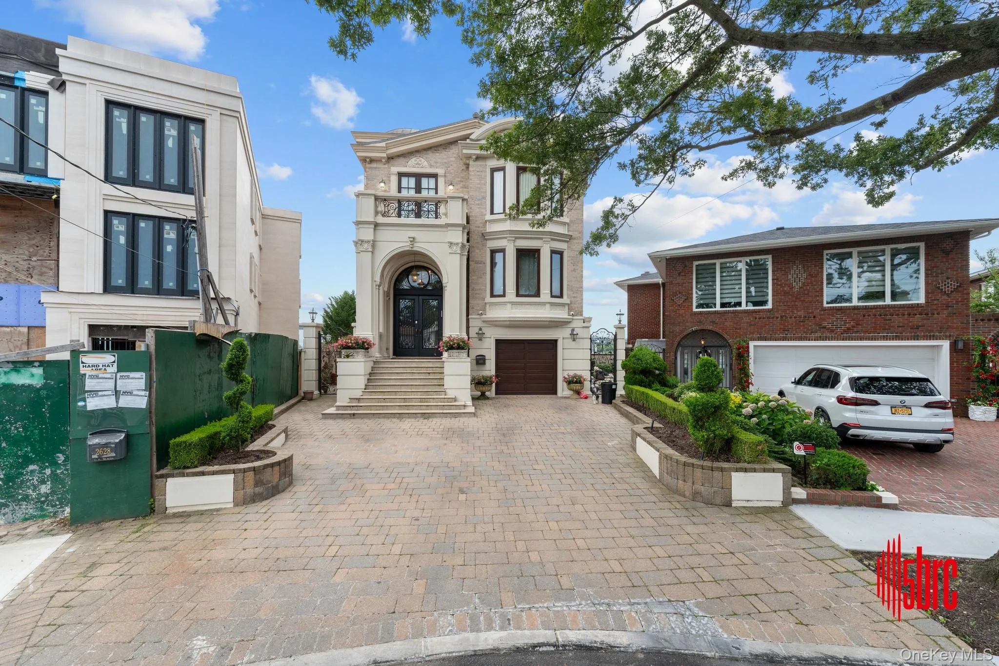 View of front of home with decorative driveway, an attached garage, brick siding, and a balcony View of front of home with decorative driveway, an attached garage, brick siding, and a balcony