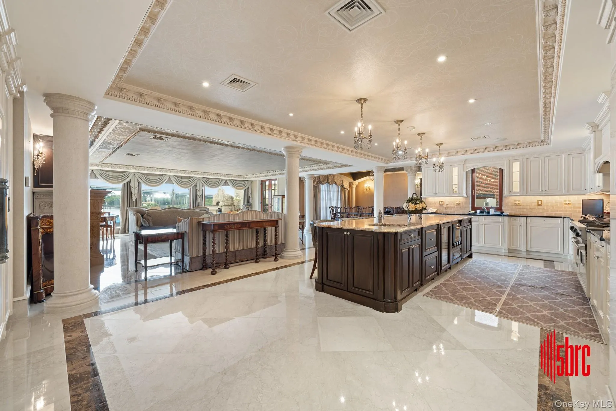 Kitchen with decorative columns, a raised ceiling, light marble finish flooring, crown molding, and recessed lighting Kitchen with decorative columns, a raised ceiling, light marble finish flooring, crown molding, and recessed lighting
