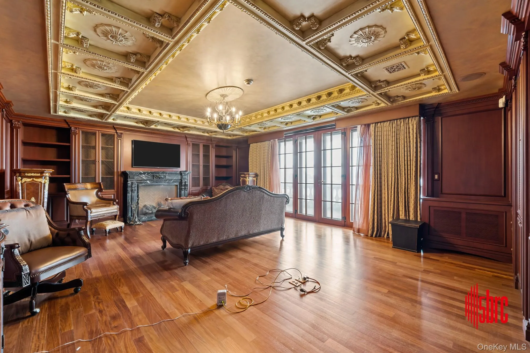 Living area featuring a high end fireplace, a chandelier, french doors, light wood finished floors, and ornamental molding Living area featuring a high end fireplace, a chandelier, french doors, light wood finished floors, and ornamental molding