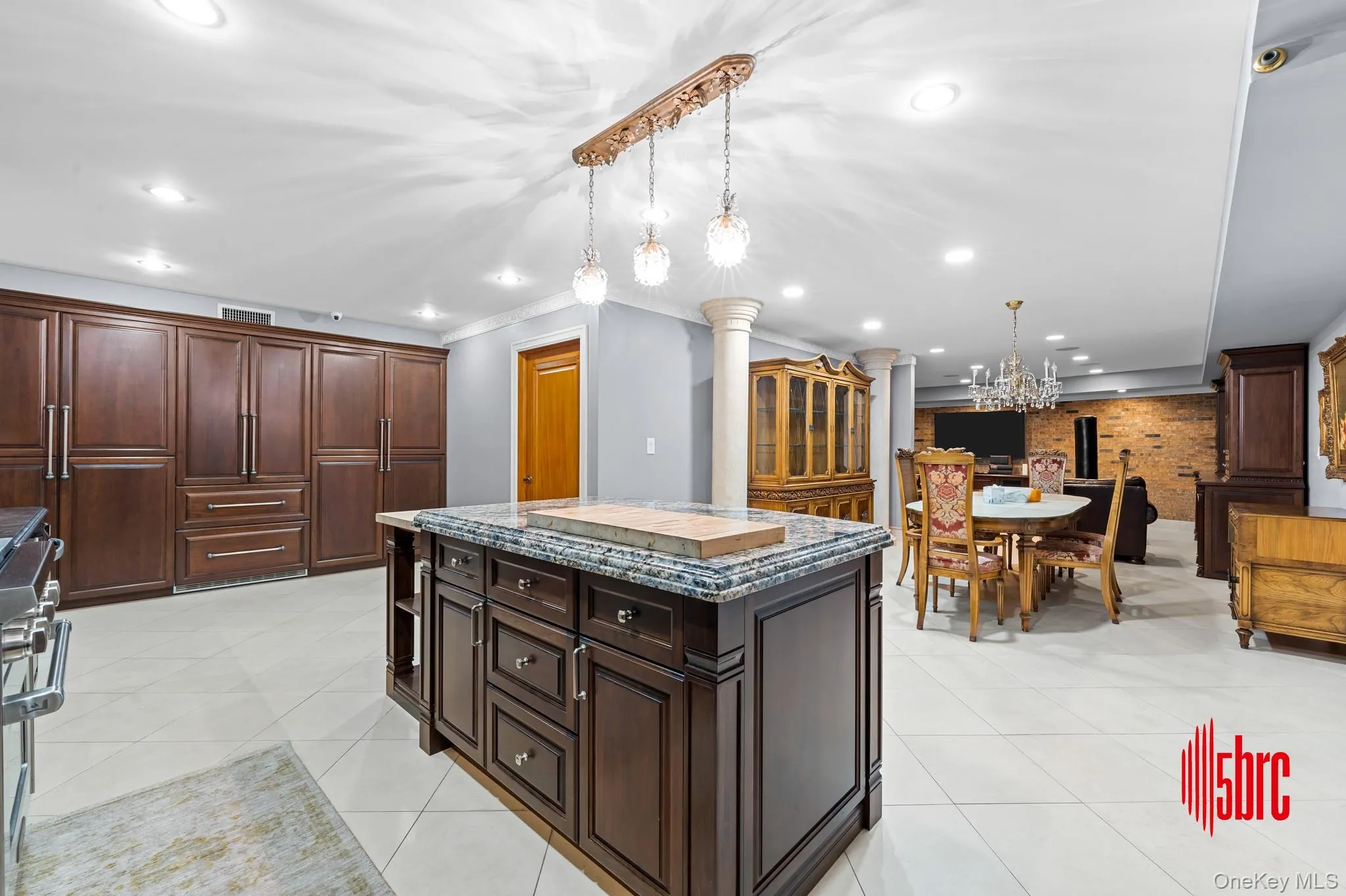 Kitchen with dark brown cabinetry, dark stone counters, recessed lighting, pendant lighting, and stainless steel range oven Kitchen with dark brown cabinetry, dark stone counters, recessed lighting, pendant lighting, and stainless steel range oven