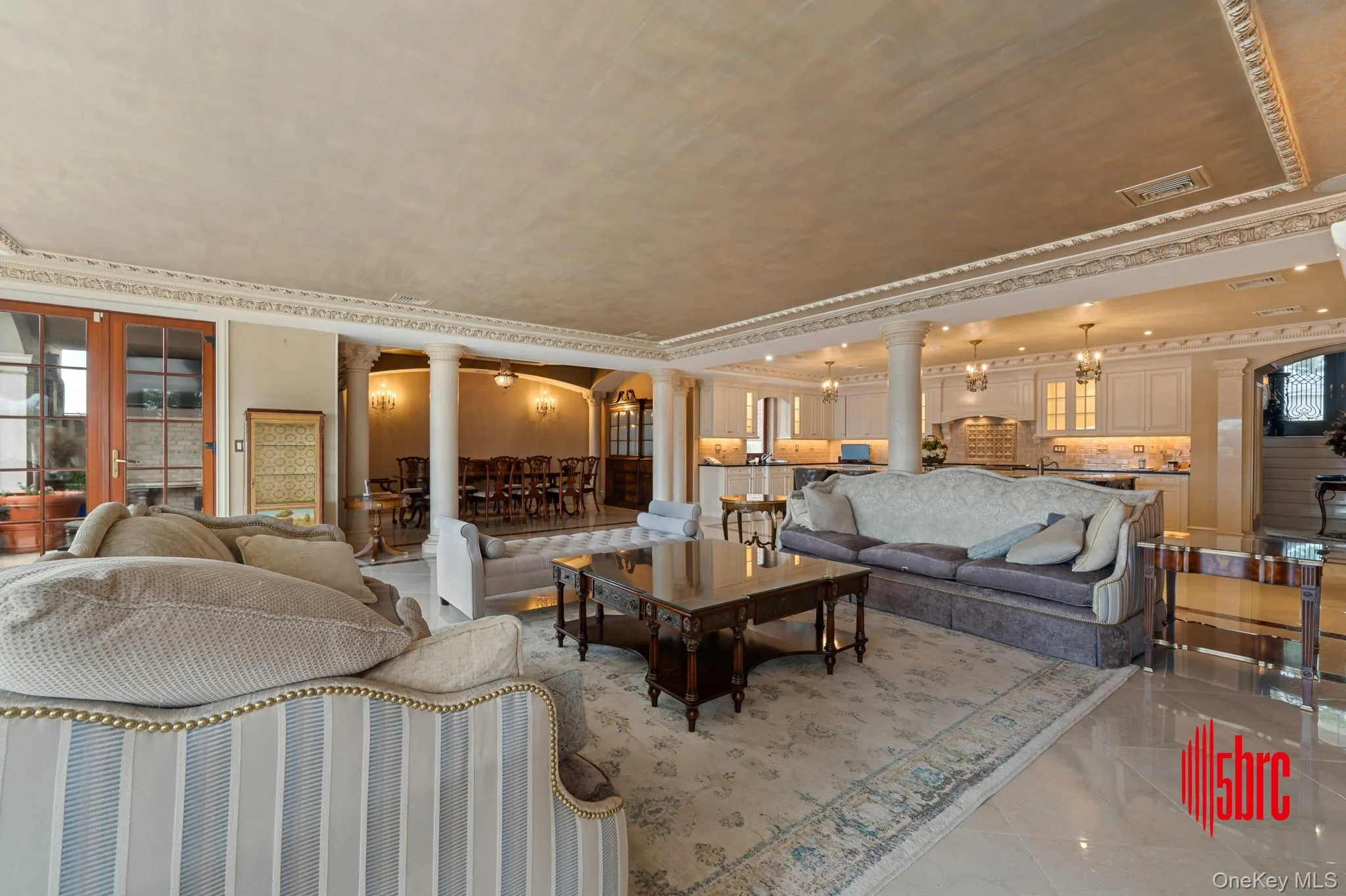 Living area with decorative columns, arched walkways, ornamental molding, and a chandelier Living area with decorative columns, arched walkways, ornamental molding, and a chandelier