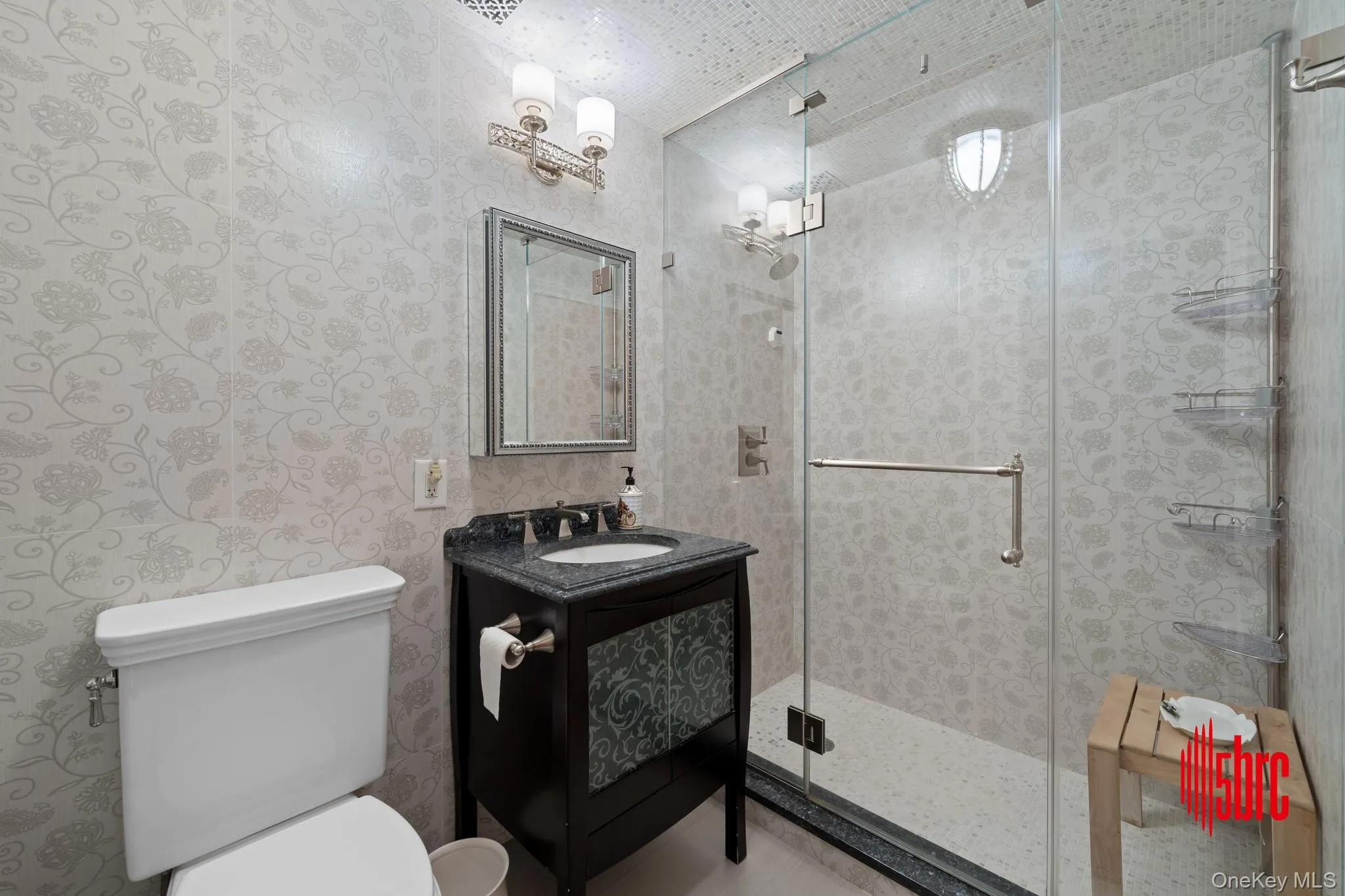 Bathroom featuring vanity, a stall shower, and wallpapered walls Bathroom featuring vanity, a stall shower, and wallpapered walls