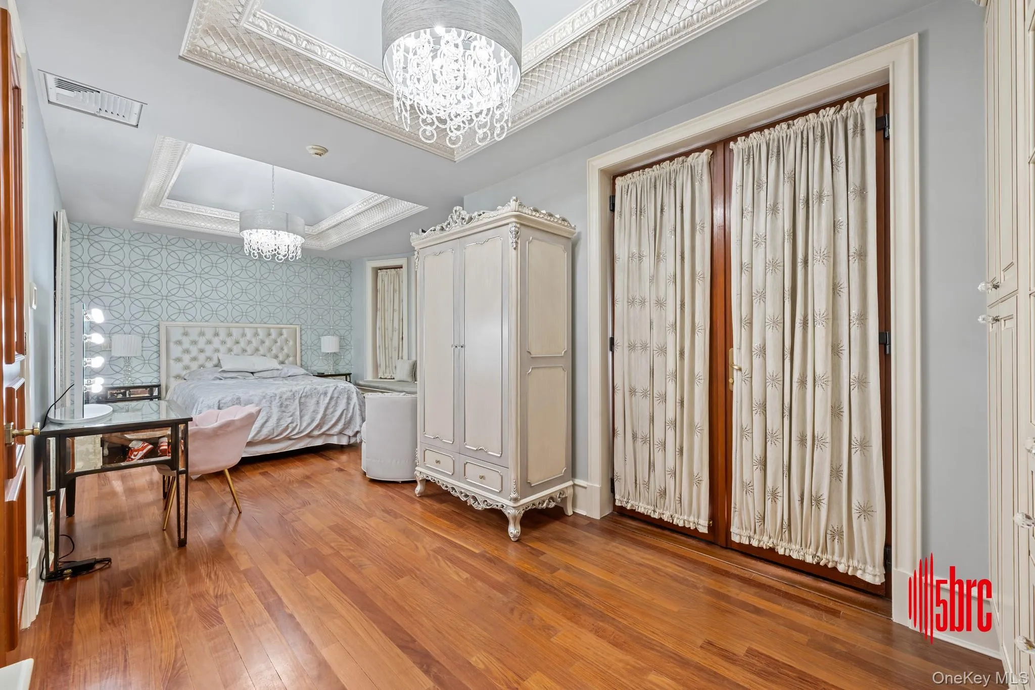 Bedroom with a tray ceiling, a chandelier, light wood-type flooring, and ornamental molding Bedroom with a tray ceiling, a chandelier, light wood-type flooring, and ornamental molding