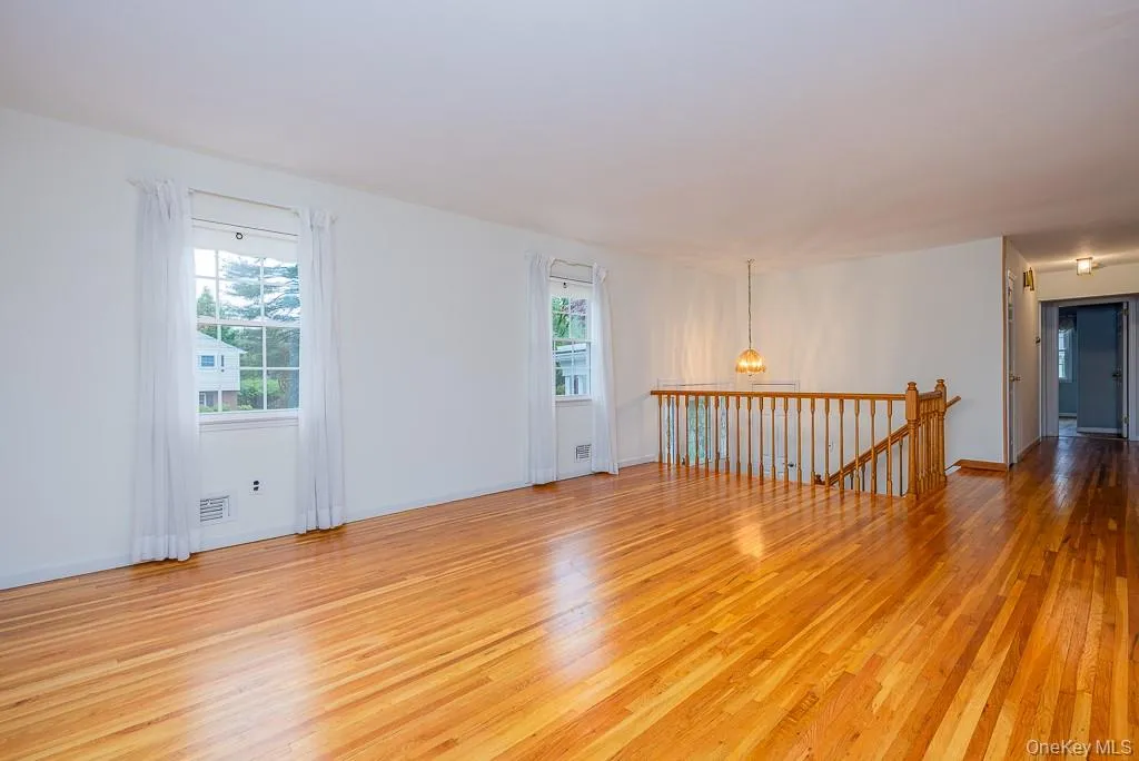Spare room featuring light wood finished floors, plenty of natural light, a chandelier, and baseboards Spare room featuring light wood finished floors, plenty of natural light, a chandelier, and baseboards