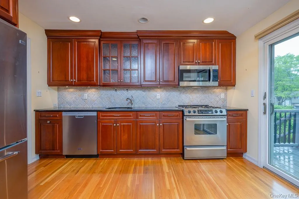 Kitchen with stainless steel appliances, light wood-style floors, a sink, tasteful backsplash, and recessed lighting Kitchen with stainless steel appliances, light wood-style floors, a sink, tasteful backsplash, and recessed lighting