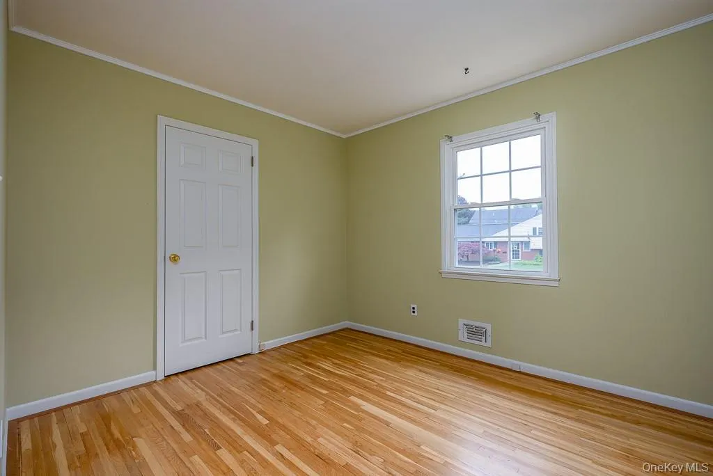 Spare room featuring baseboards, ornamental molding, and light wood-style flooring Spare room featuring baseboards, ornamental molding, and light wood-style flooring